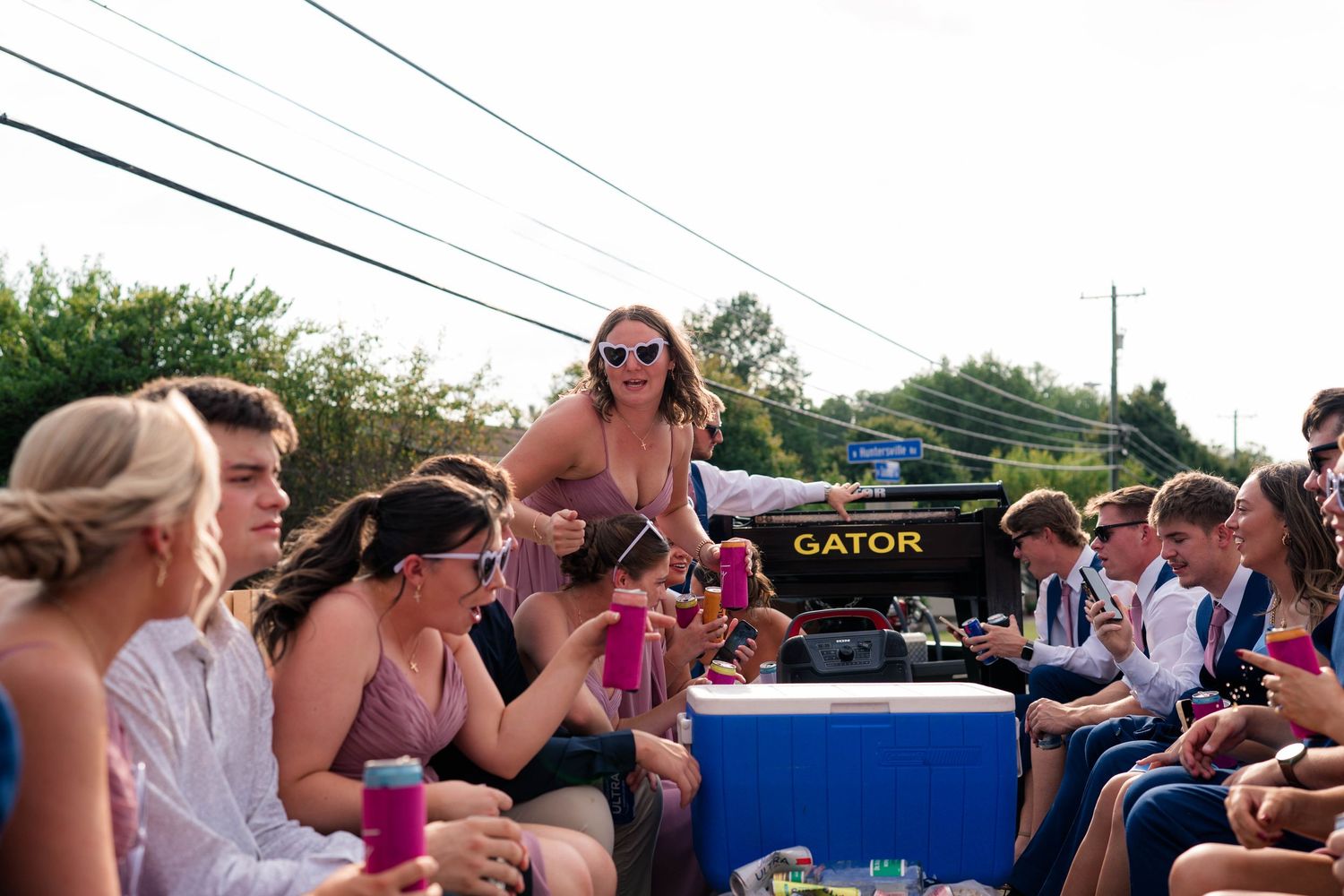 Wedding guests in formal attire socializing on a flatbed truck at an outdoor reception.