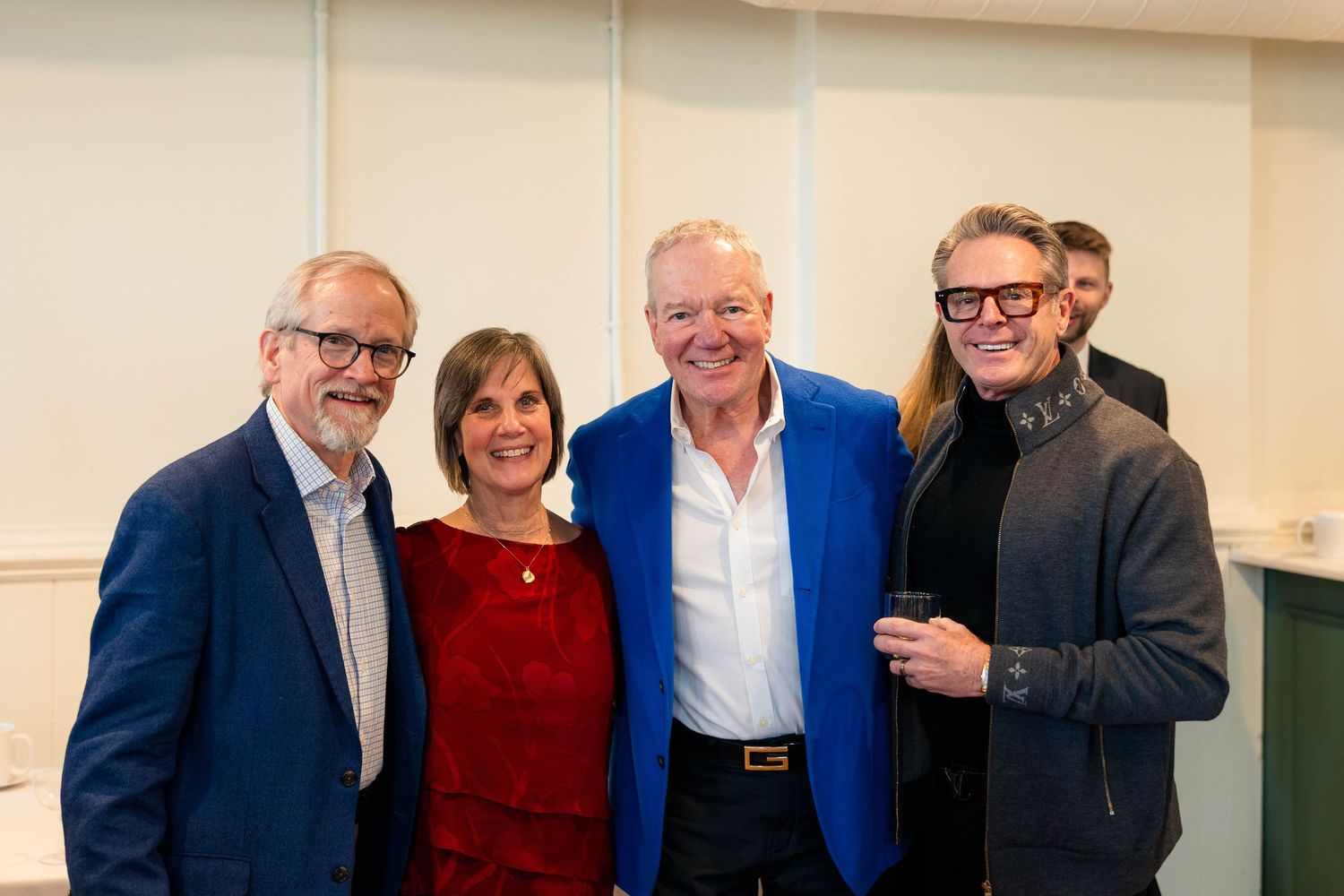 Four adults posing together smiling at a formal social event.