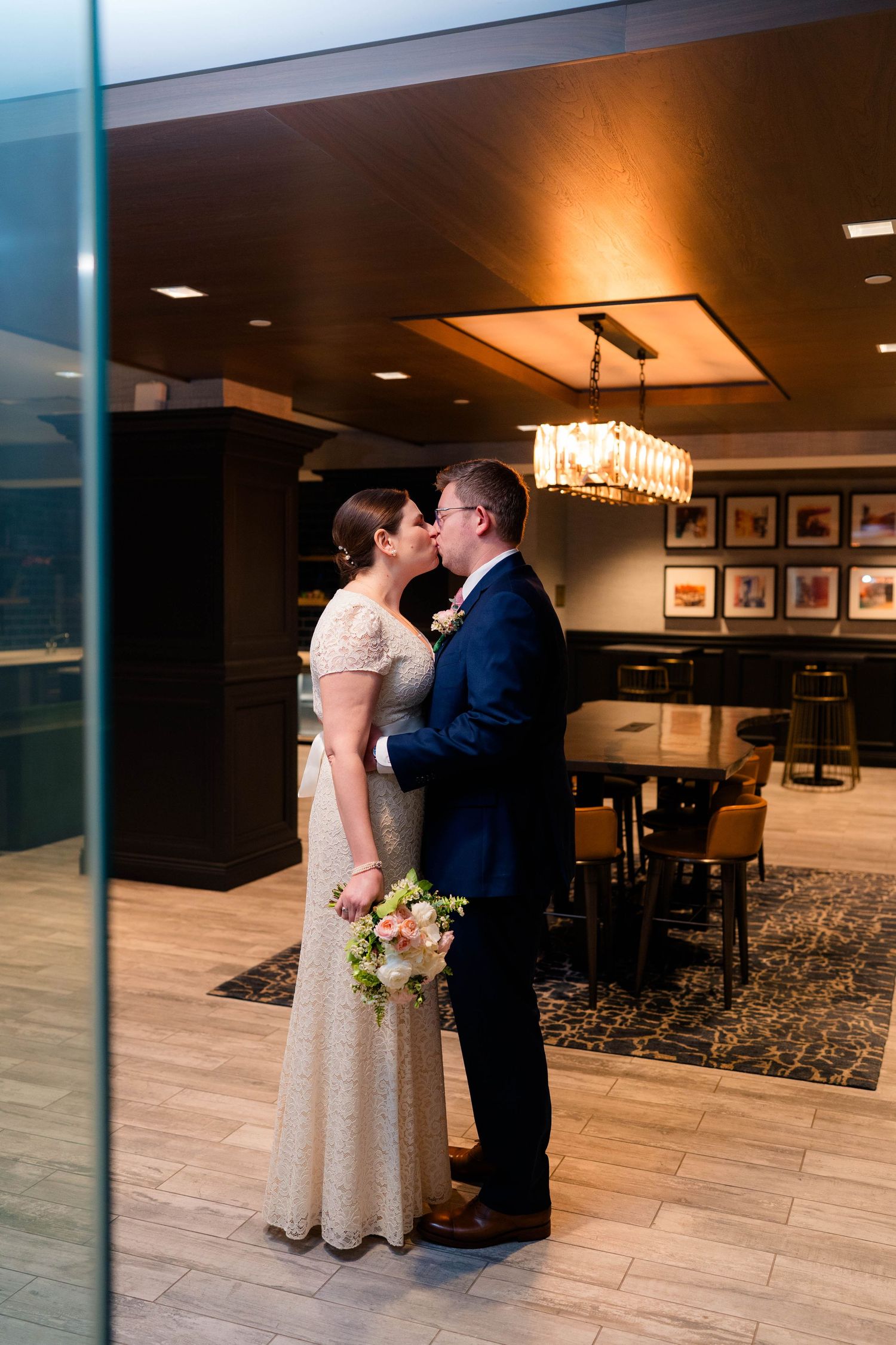 Bride and groom share their first kiss as a married couple in an elegantly lit hotel interior.