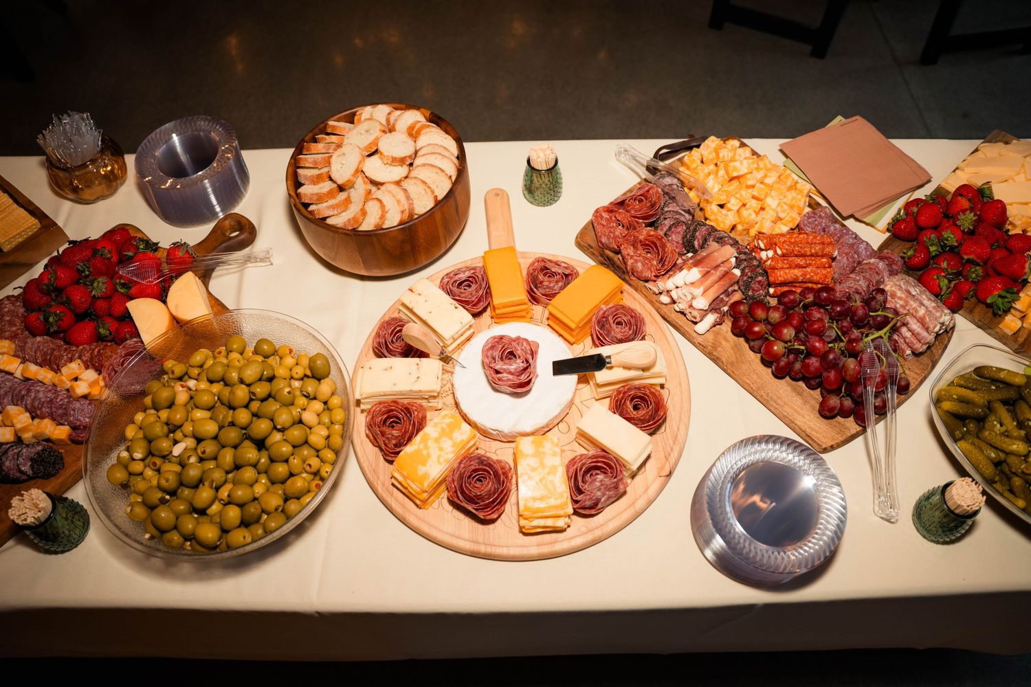 Elegant wedding charcuterie spread with cheese, meats, fruits, and olives on white table.