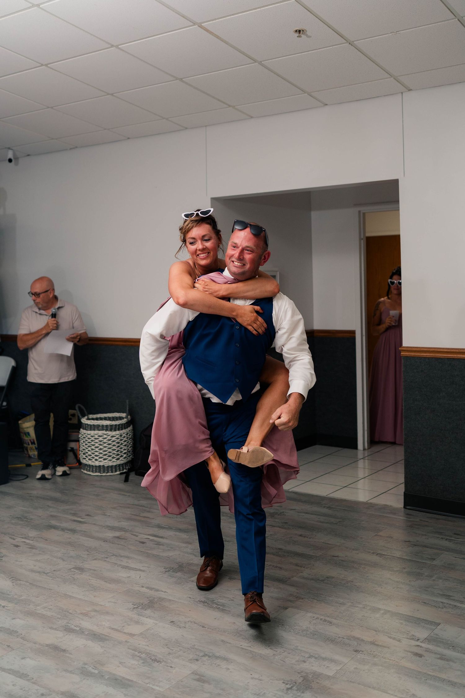Groom gives bridesmaid a piggyback ride on the dance floor during wedding reception.