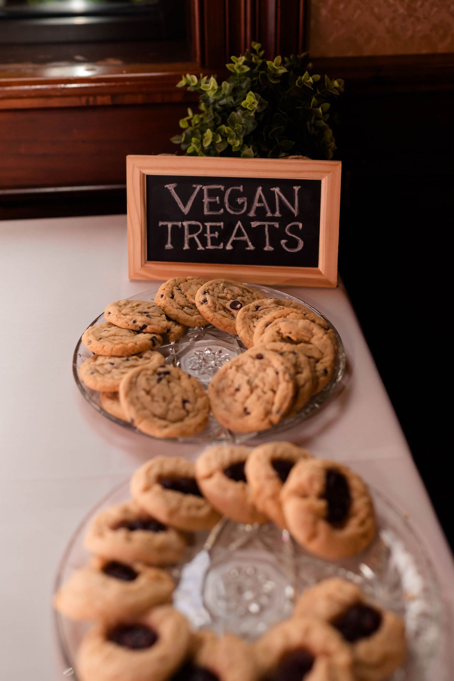 Vegan treats display with chocolate chip cookies on glass plates at wedding.