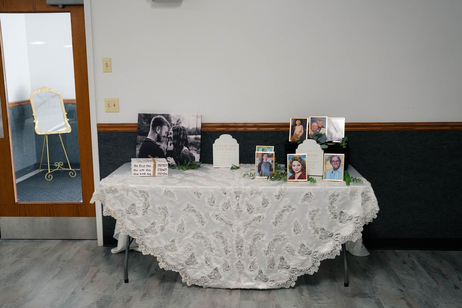 Wedding memory table with lace tablecloth displaying framed photos and keepsakes at reception.