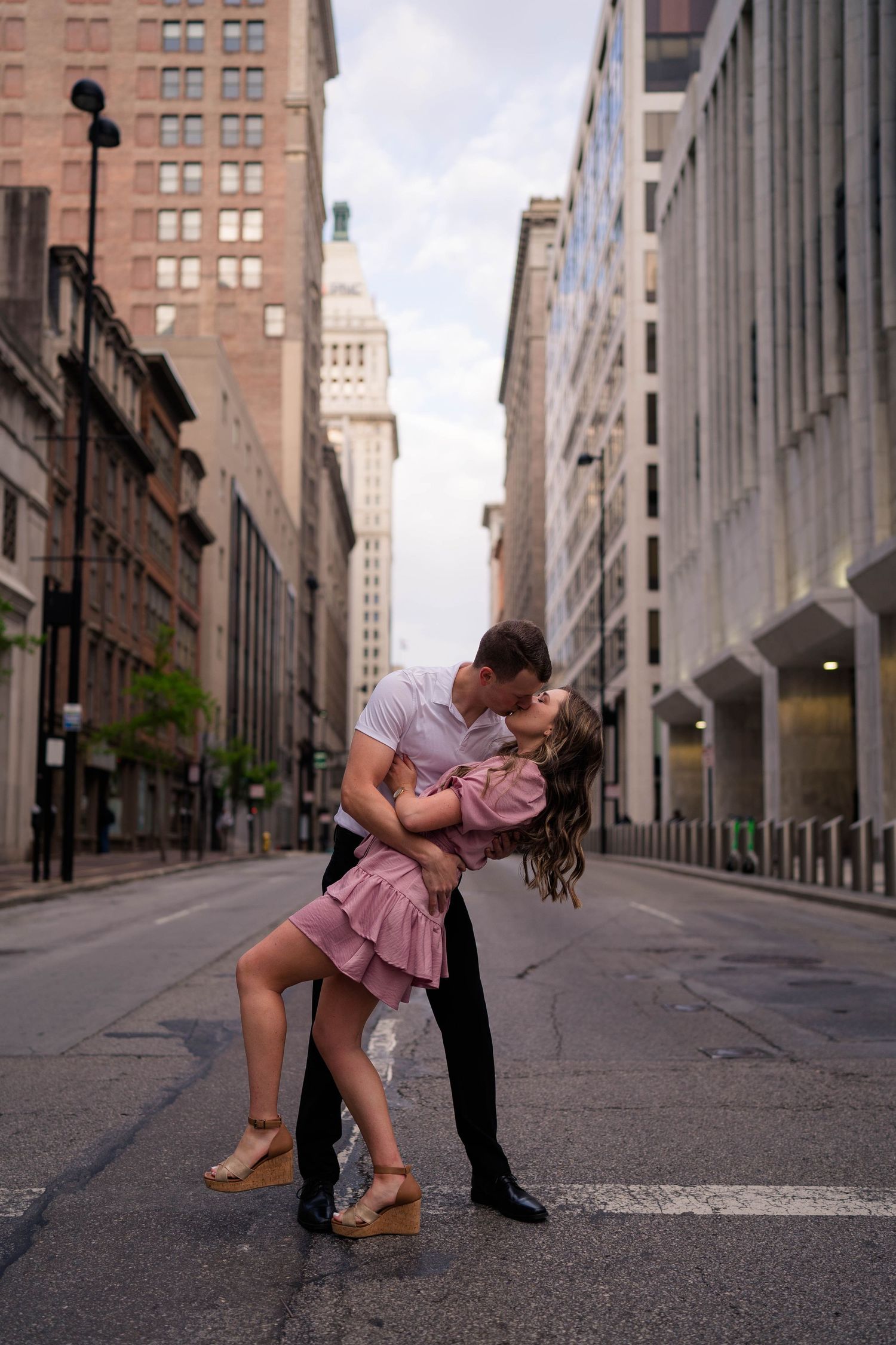 Couple shares a romantic dip kiss in the middle of an urban city street.