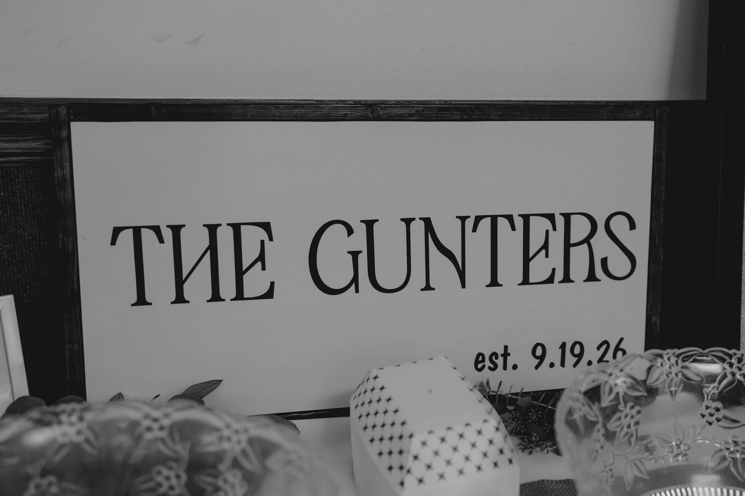 Black and white sign reading The Gunters est. 9.19.26 displayed at wedding reception table.