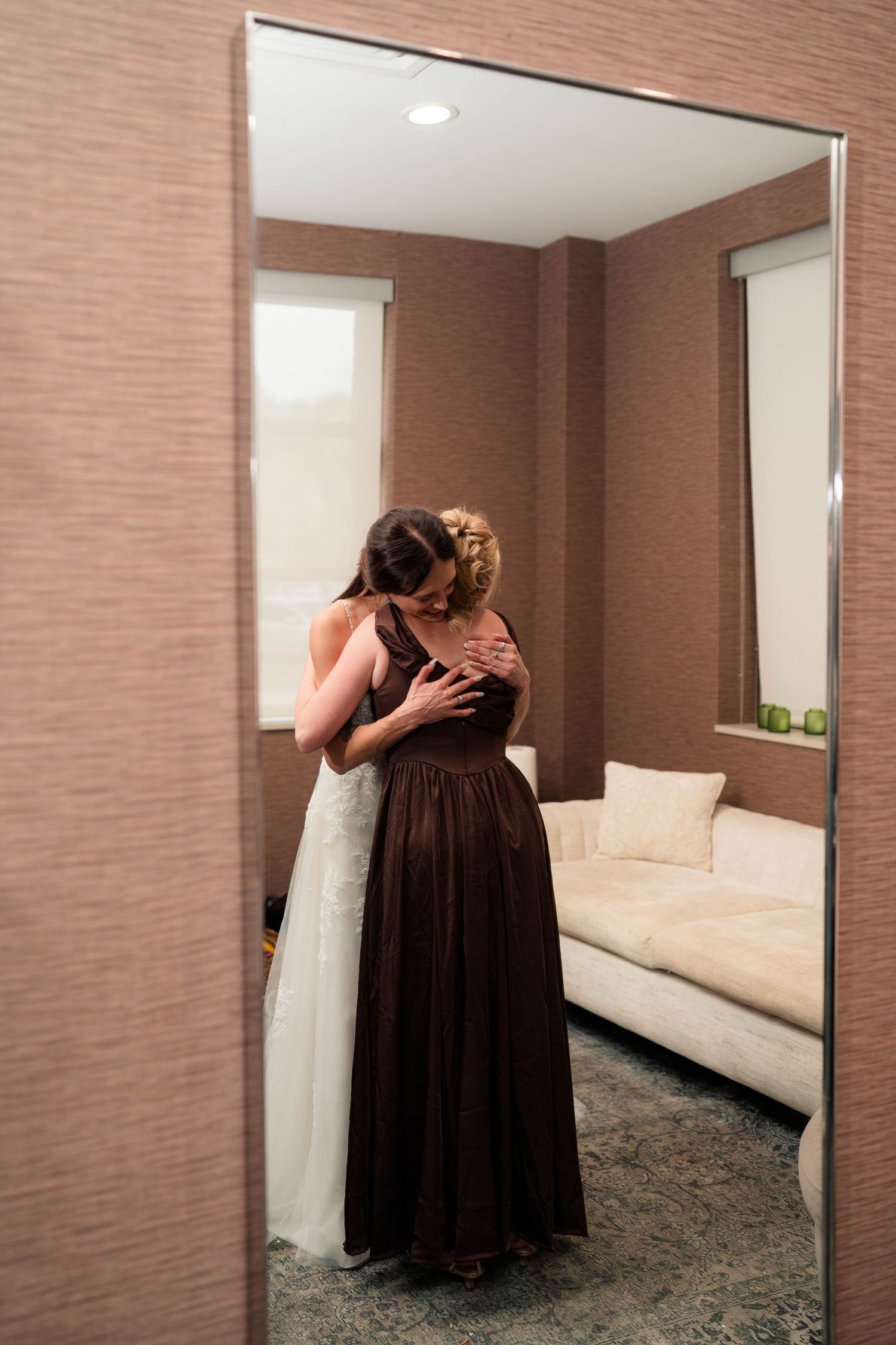 Bride and mother sharing an emotional hug in a hotel room before the wedding ceremony.