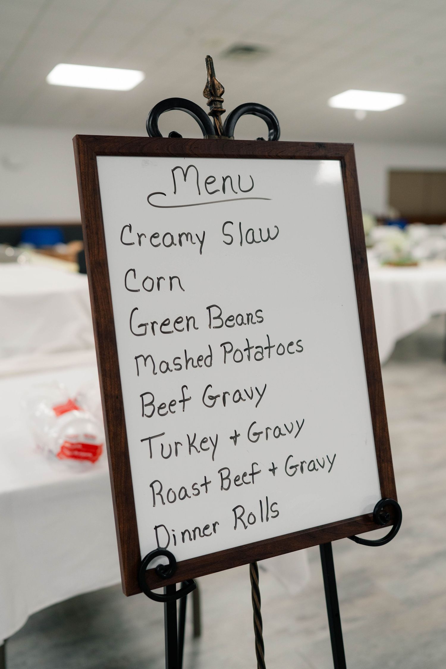 Handwritten wedding reception menu board listing creamy slaw, turkey, roast beef, and dinner rolls.