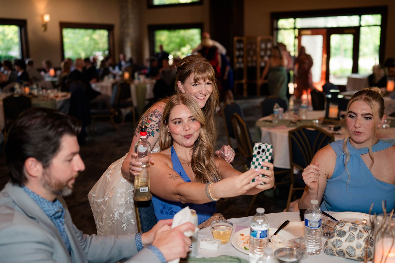 Wedding guests taking a selfie together at a reception dinner table.