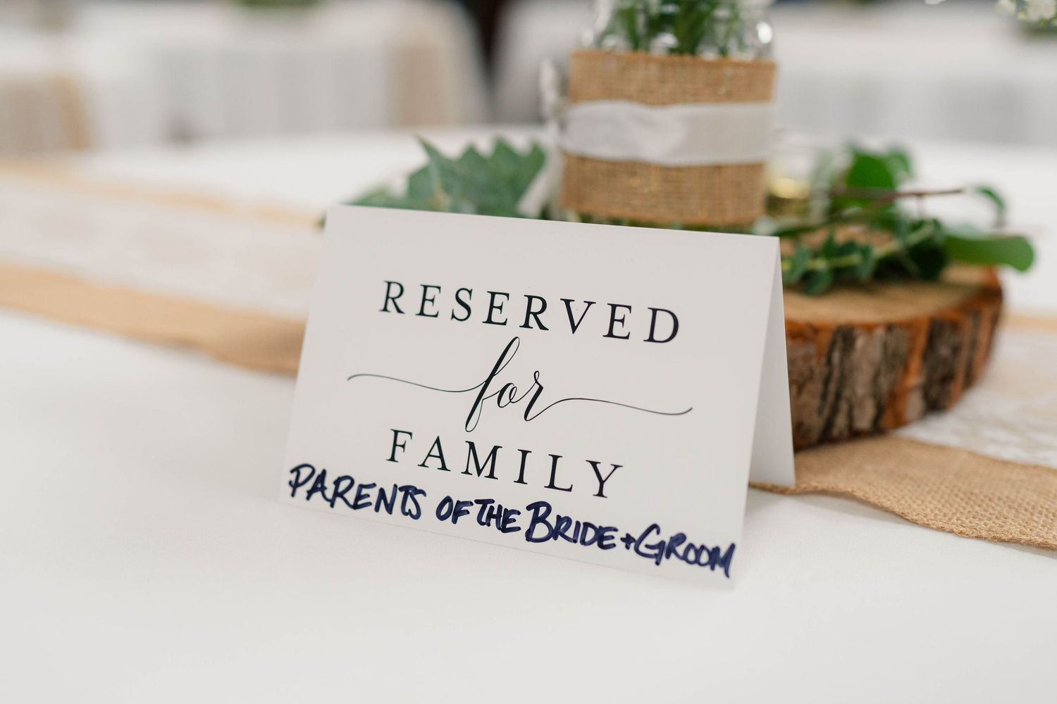 Reserved for family parents of the bride and groom place card on elegant white wedding reception table.