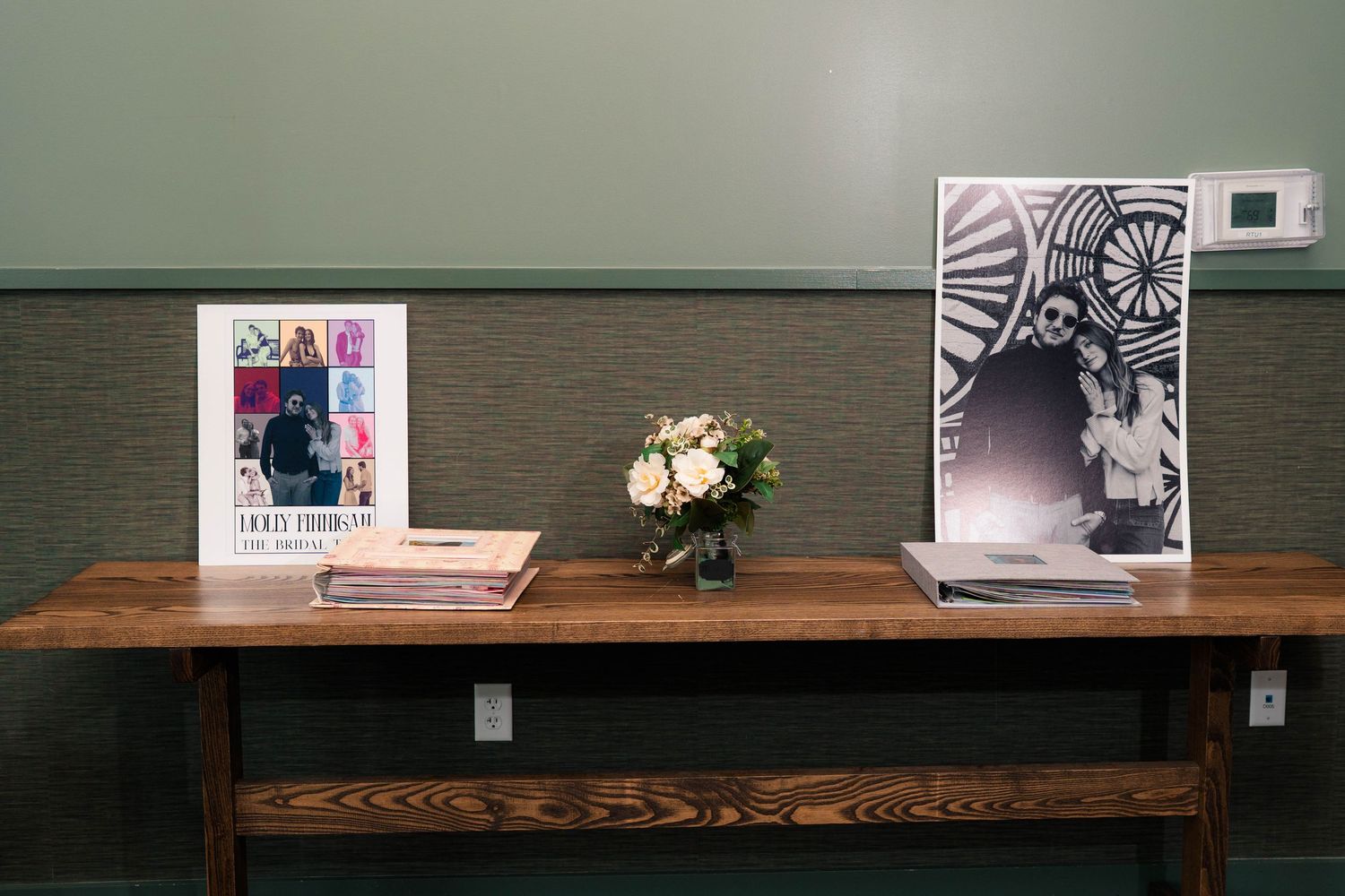 Wedding guest book table with floral arrangement and decorative books at reception venue.