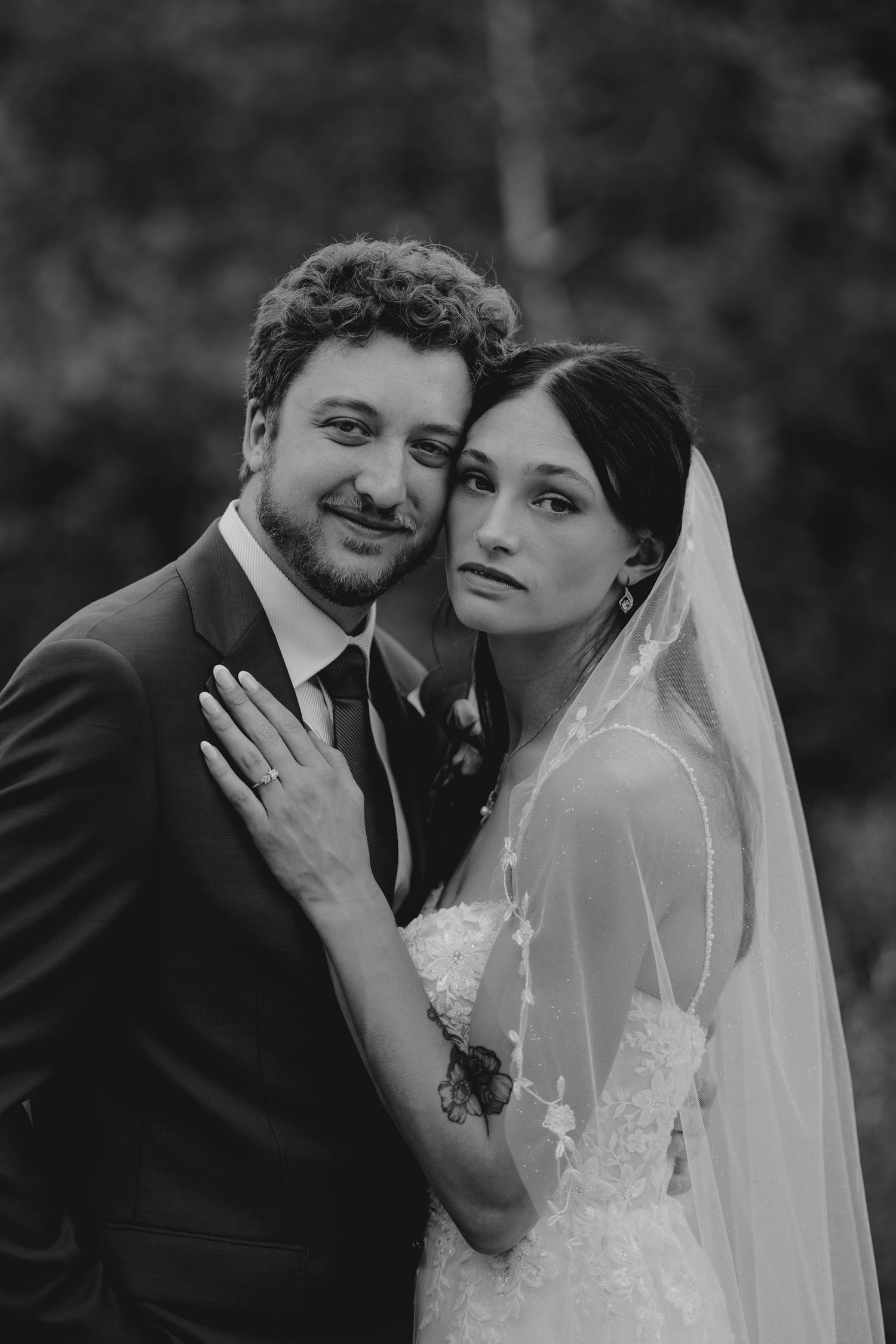 Black and white portrait of bride and groom embracing tenderly outdoors on their wedding day.