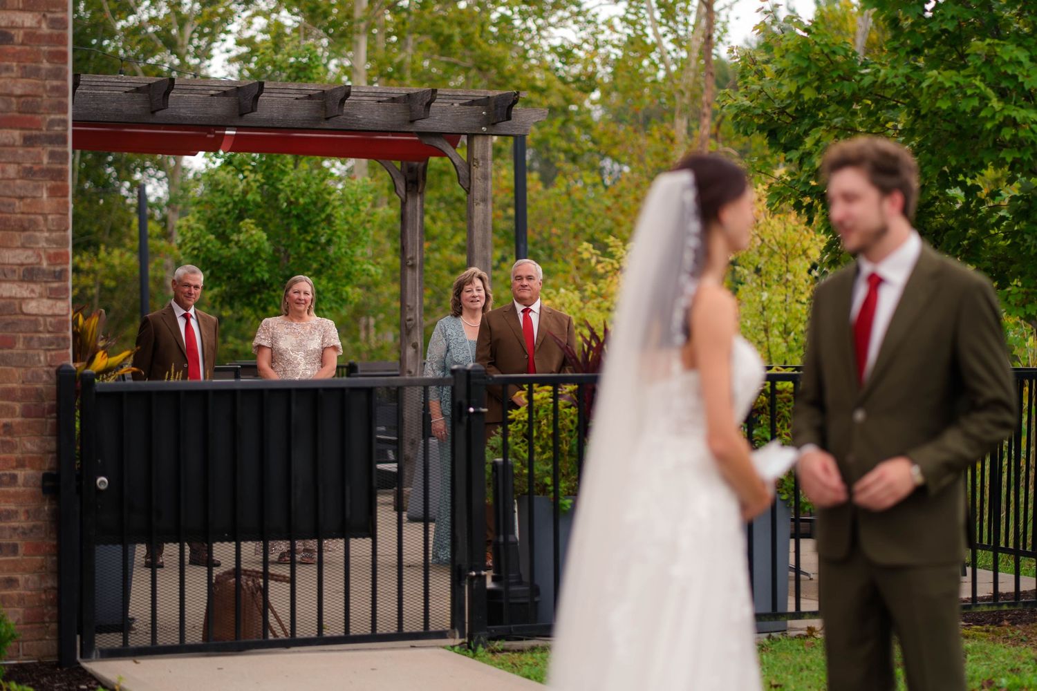 Bride and groom sharing first look moment while families watch from balcony.