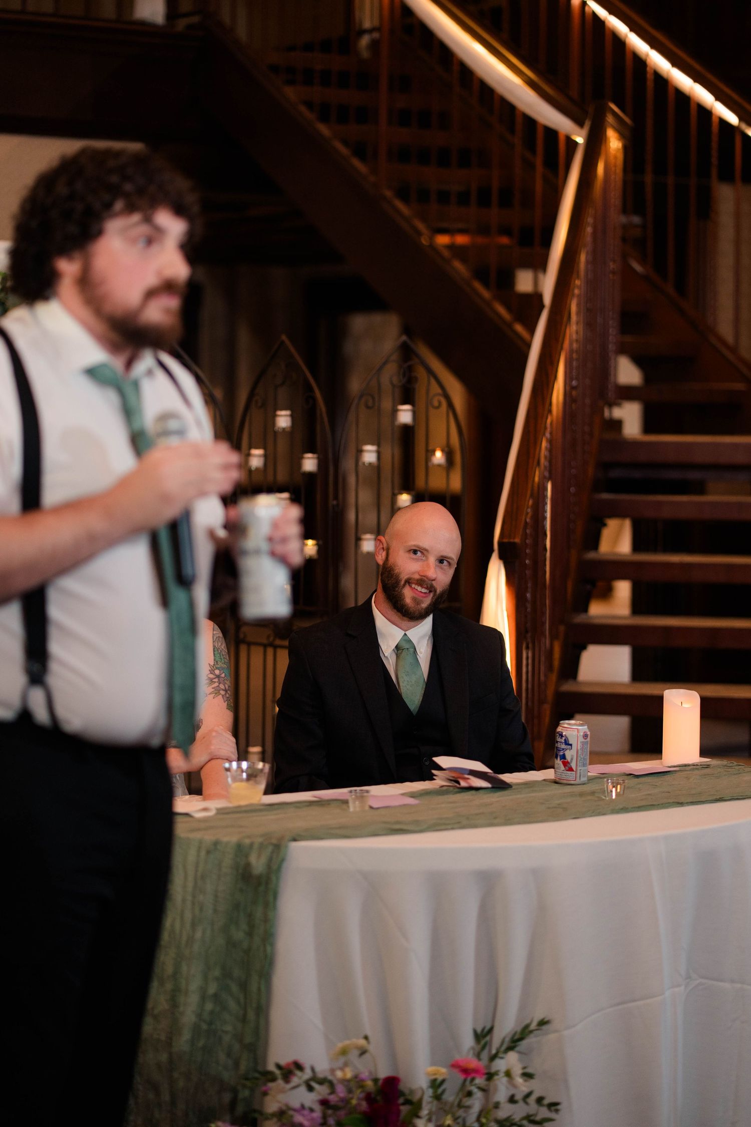 Groom smiling at guest giving a toast at elegant wedding reception venue.