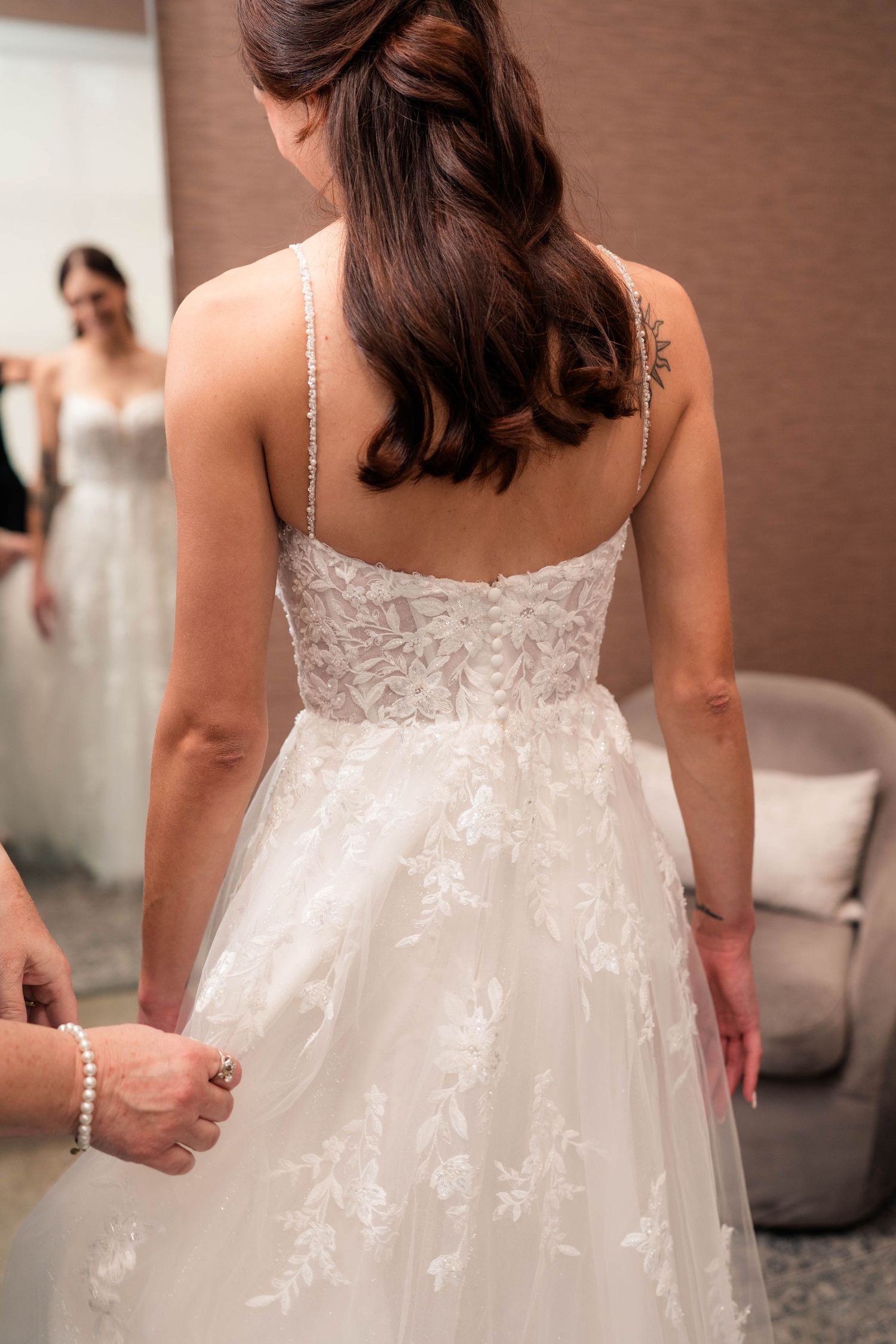 Bride in white lace spaghetti strap wedding dress viewed from behind with half-up hairstyle.