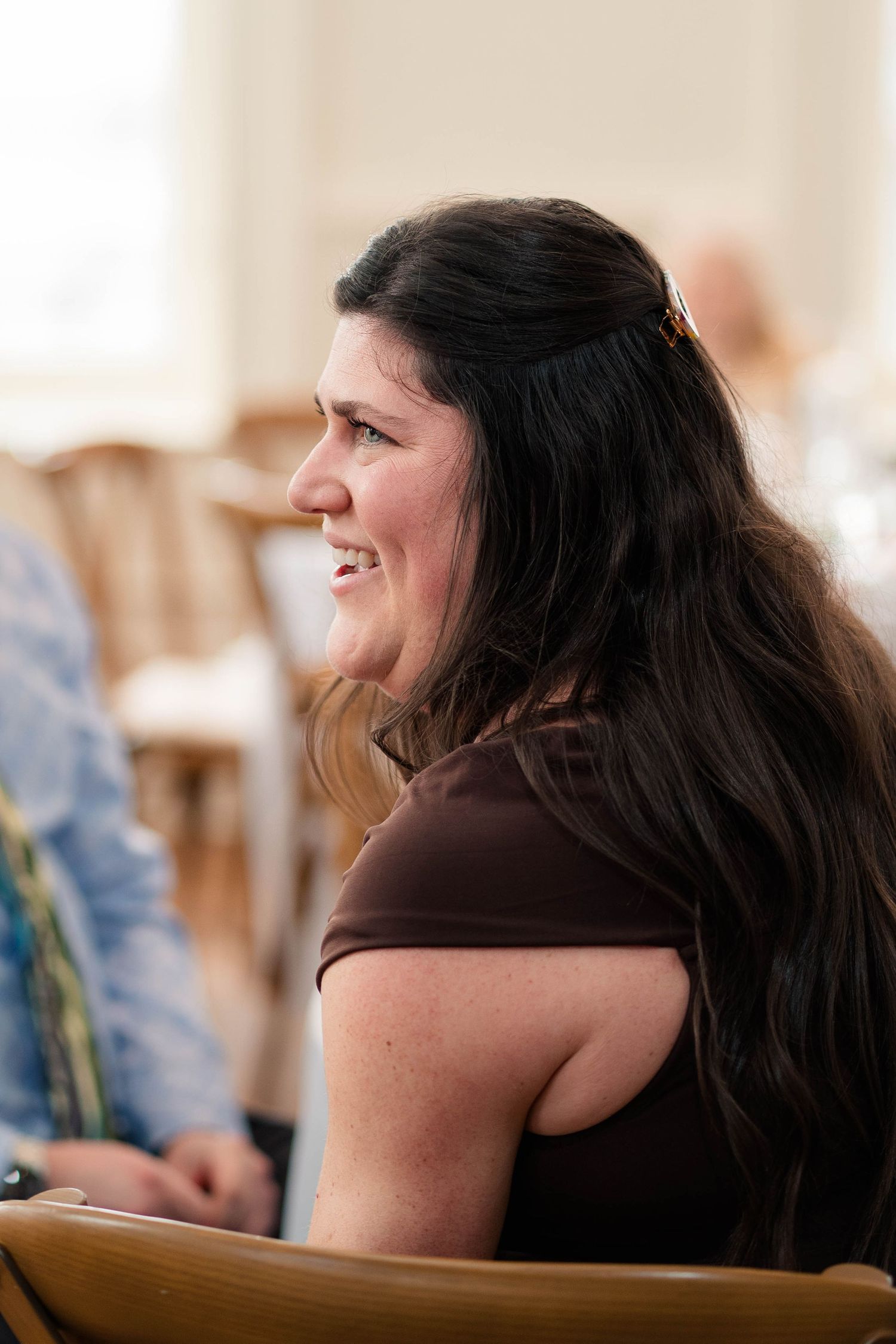 Young woman with long dark hair smiling and laughing at a wedding reception event.