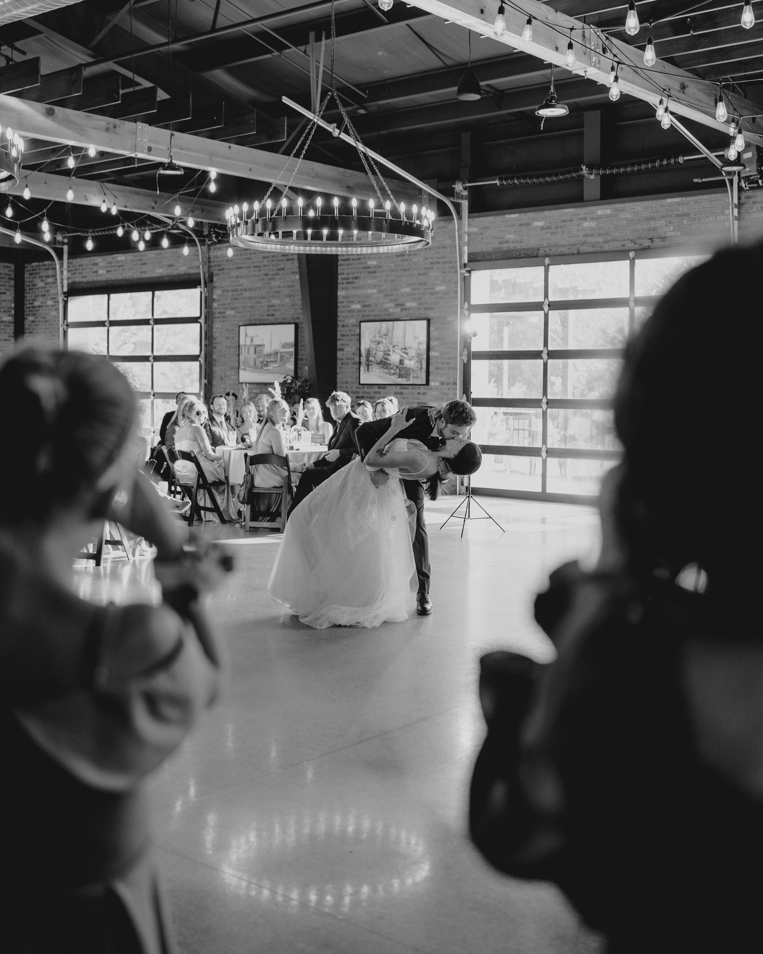 Black and white photo of bride and groom sharing a dip kiss on the dance floor during their first dance.