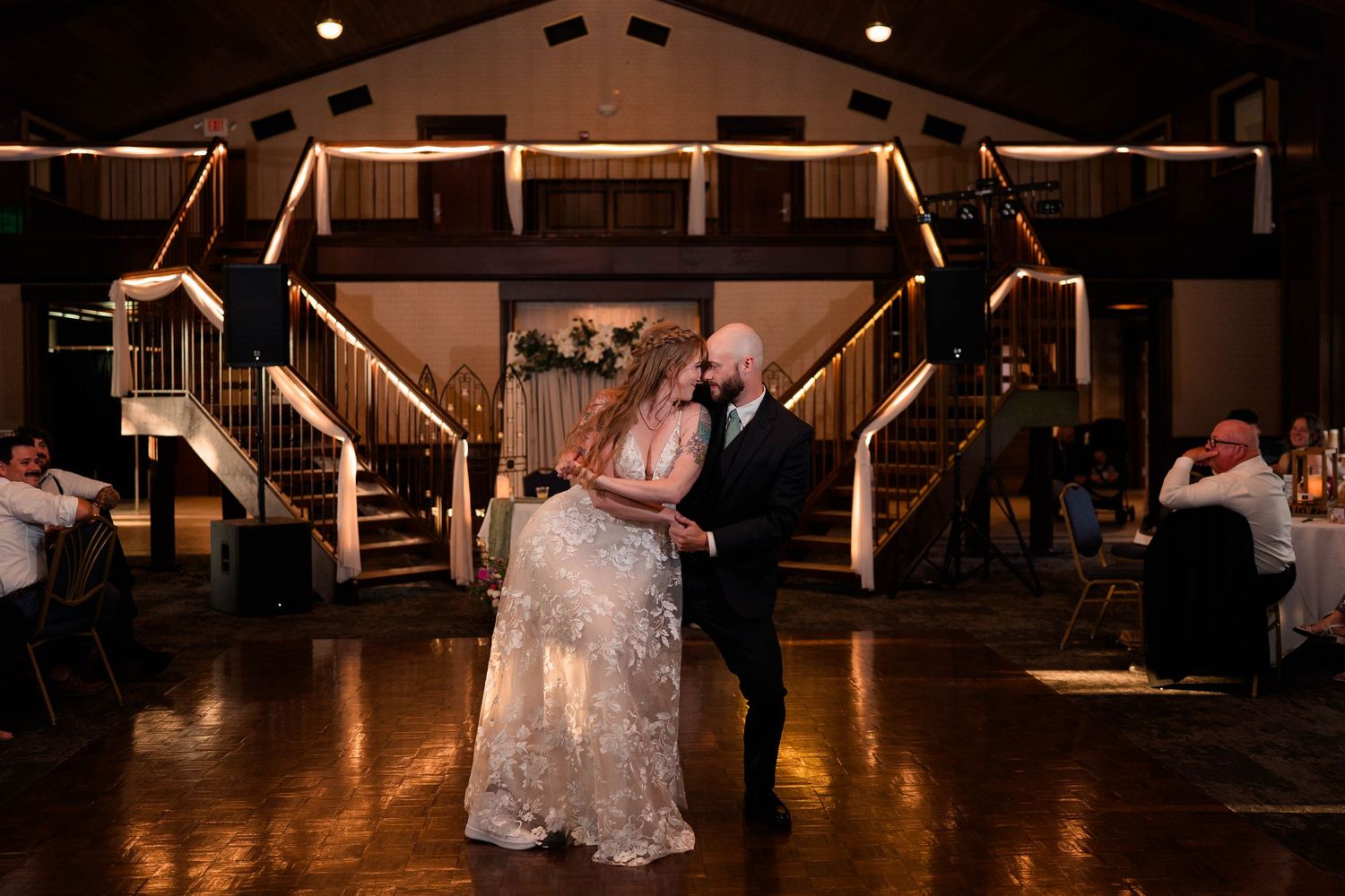 Bride and groom share romantic dip during first dance at elegant wedding reception.
