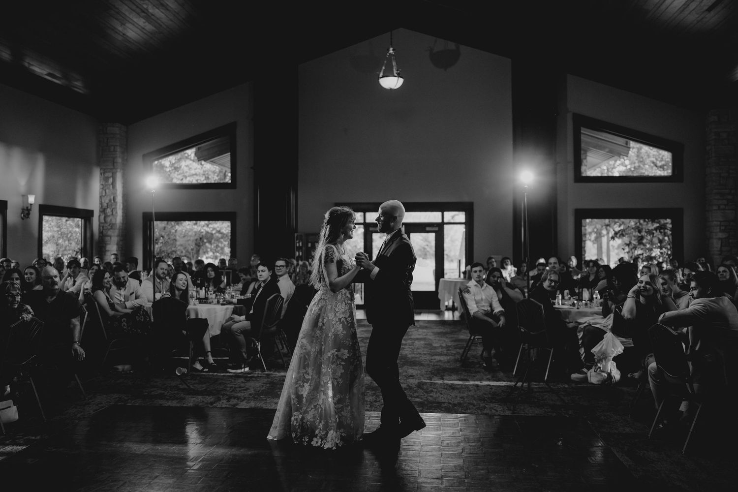 Black and white photo of bride and groom sharing first dance at wedding reception.