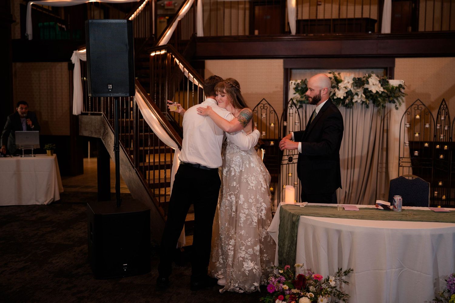 Bride and groom share an emotional hug during first dance at elegant indoor wedding reception venue.