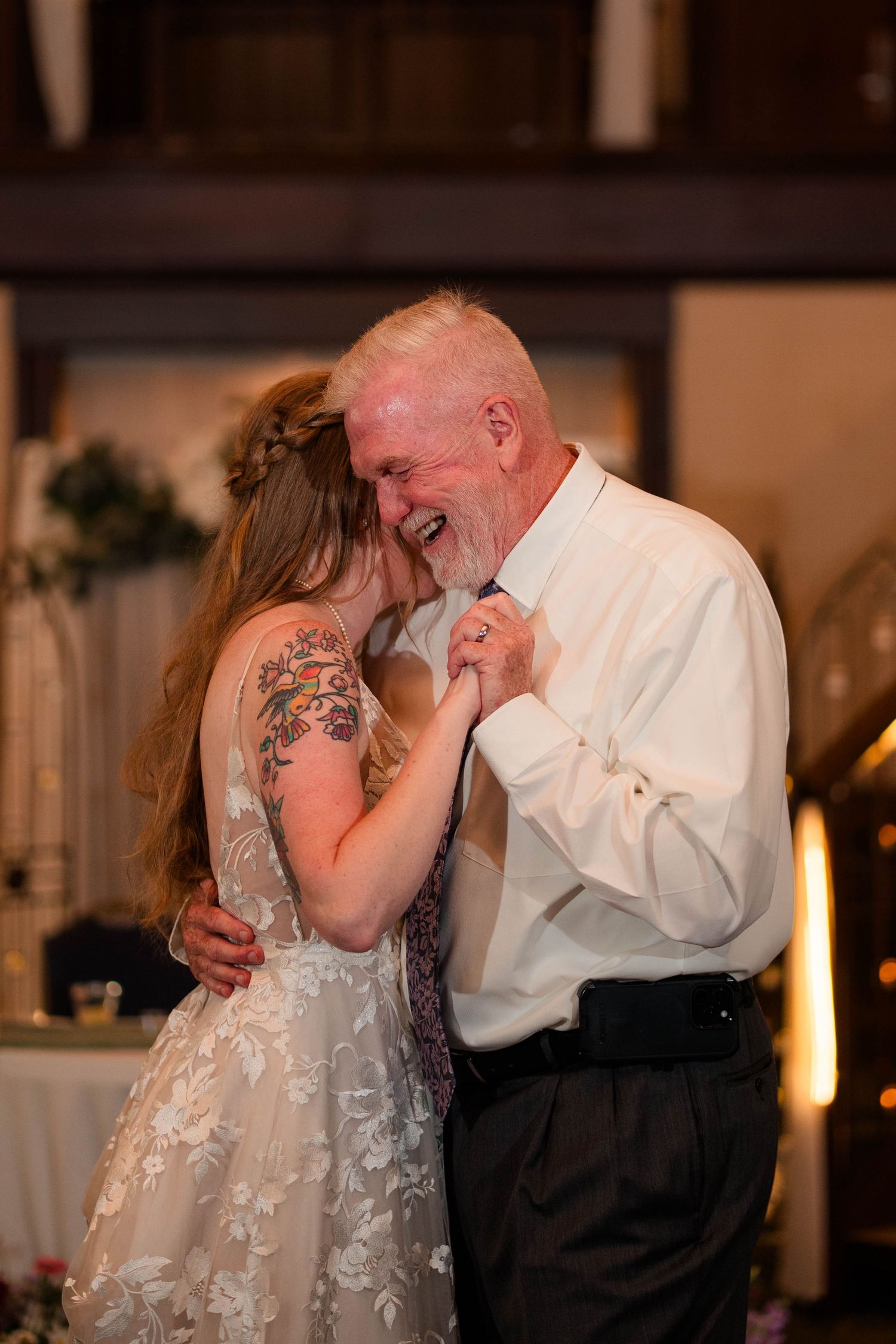 Bride and elderly man share emotional father-daughter dance at wedding reception.