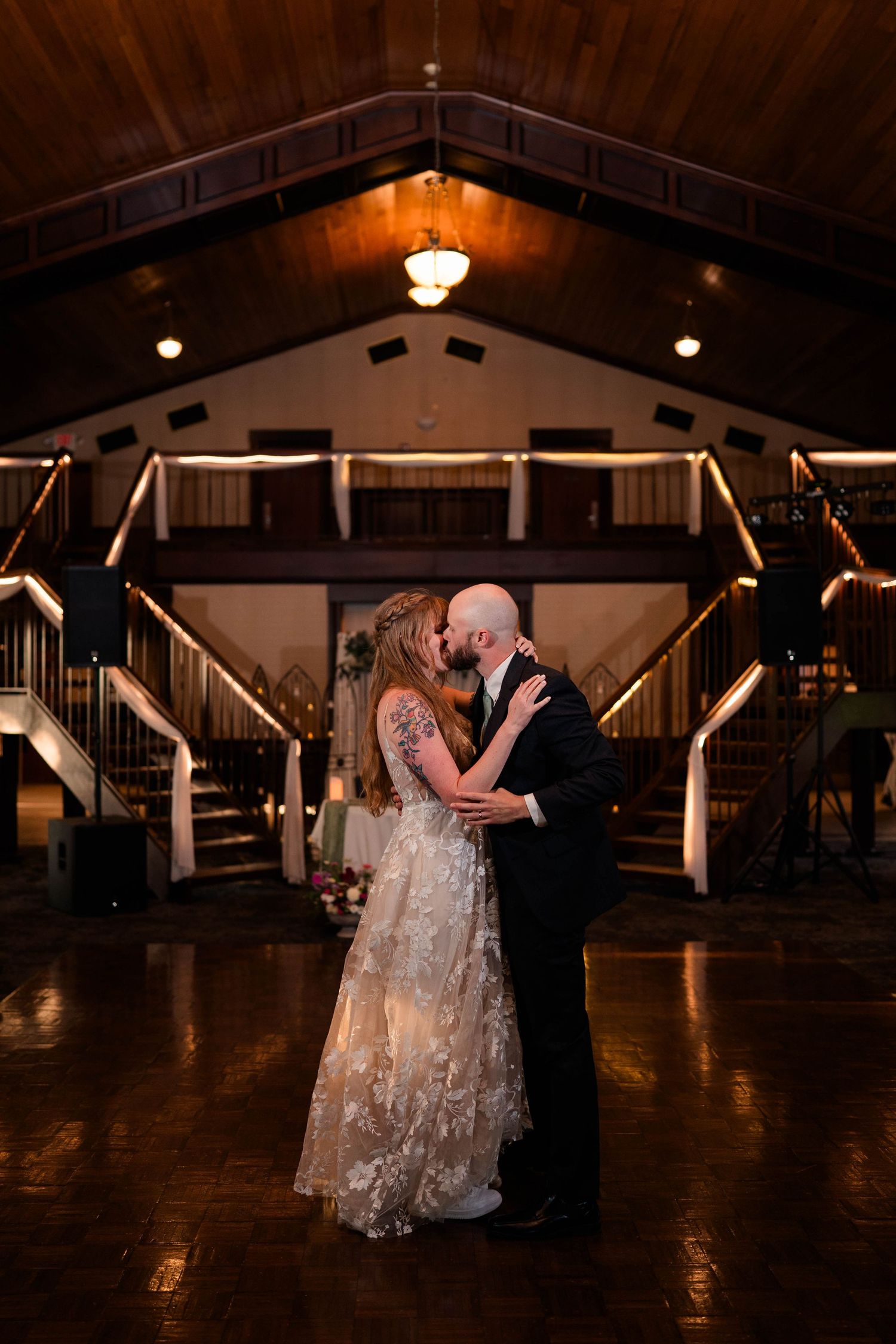 Newlyweds share a romantic kiss on the dance floor of a beautifully lit wedding reception venue.