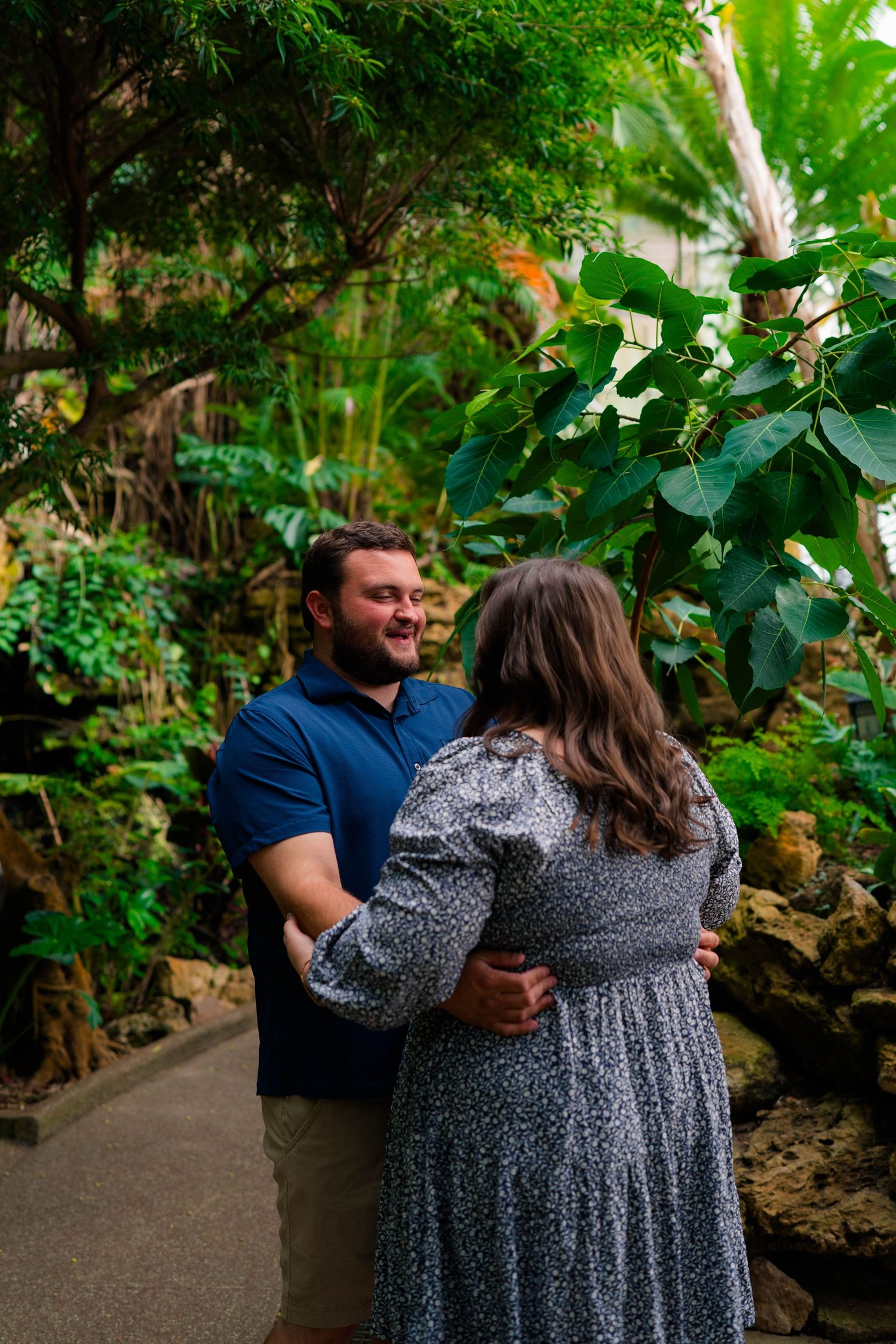 Happy couple embracing and smiling at each other surrounded by tropical greenery and rock formations.