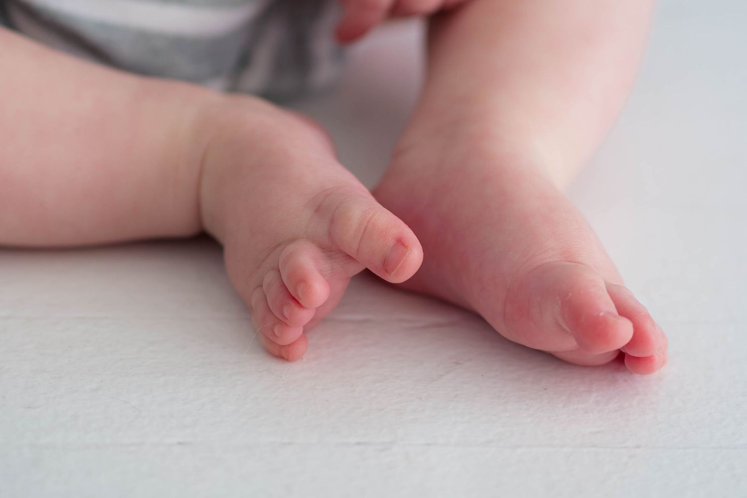 Close-up of tiny newborn baby feet resting on soft white surface.