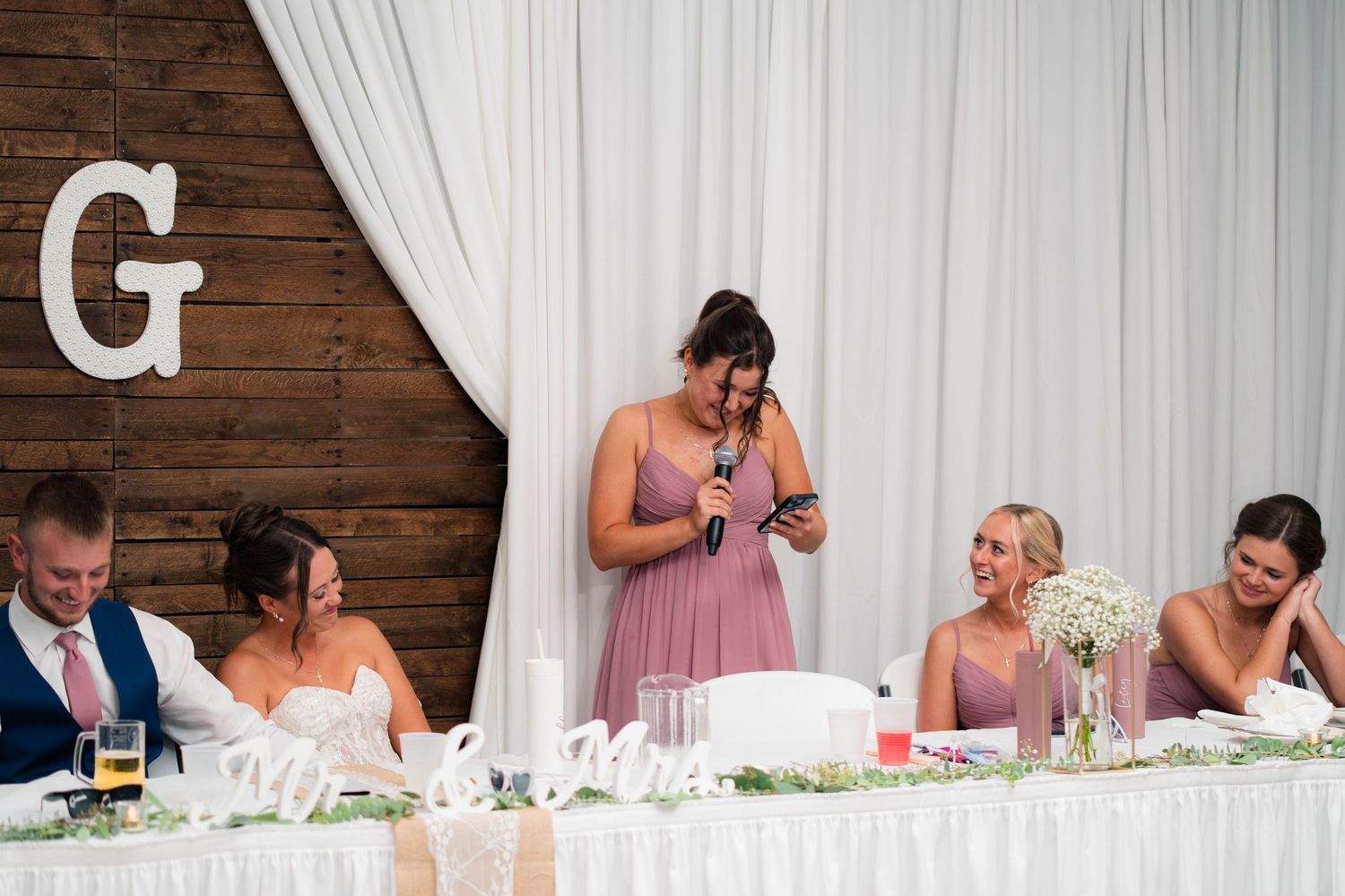 Bridesmaid reads an emotional speech at the wedding head table during the reception.