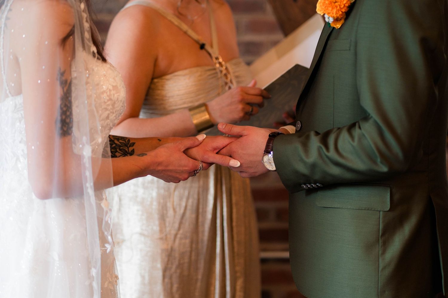 Bride and groom exchange rings during an intimate wedding ceremony while an officiant reads vows.