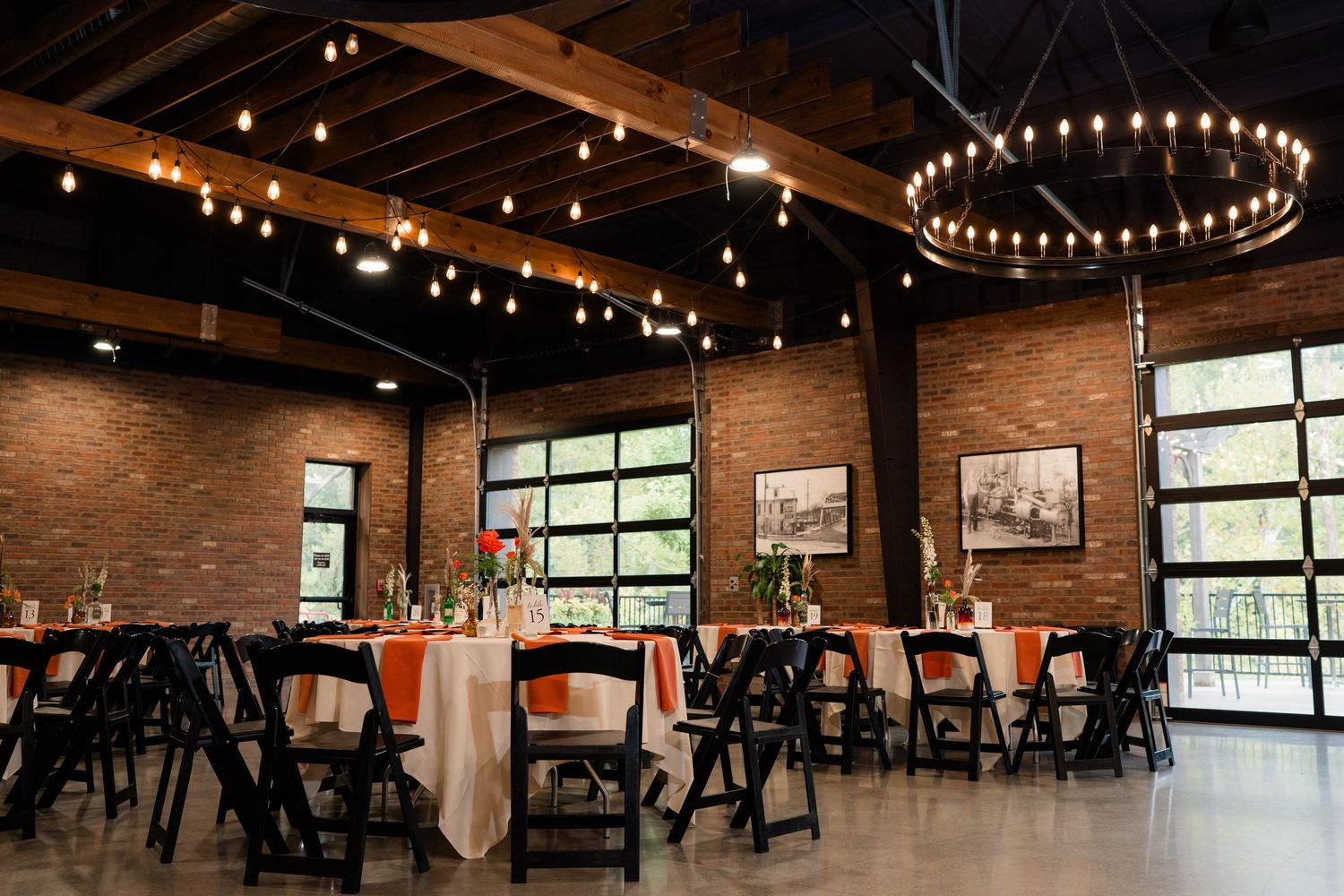 Elegant wedding reception setup in rustic brick venue with round chandeliers and peach table linens.