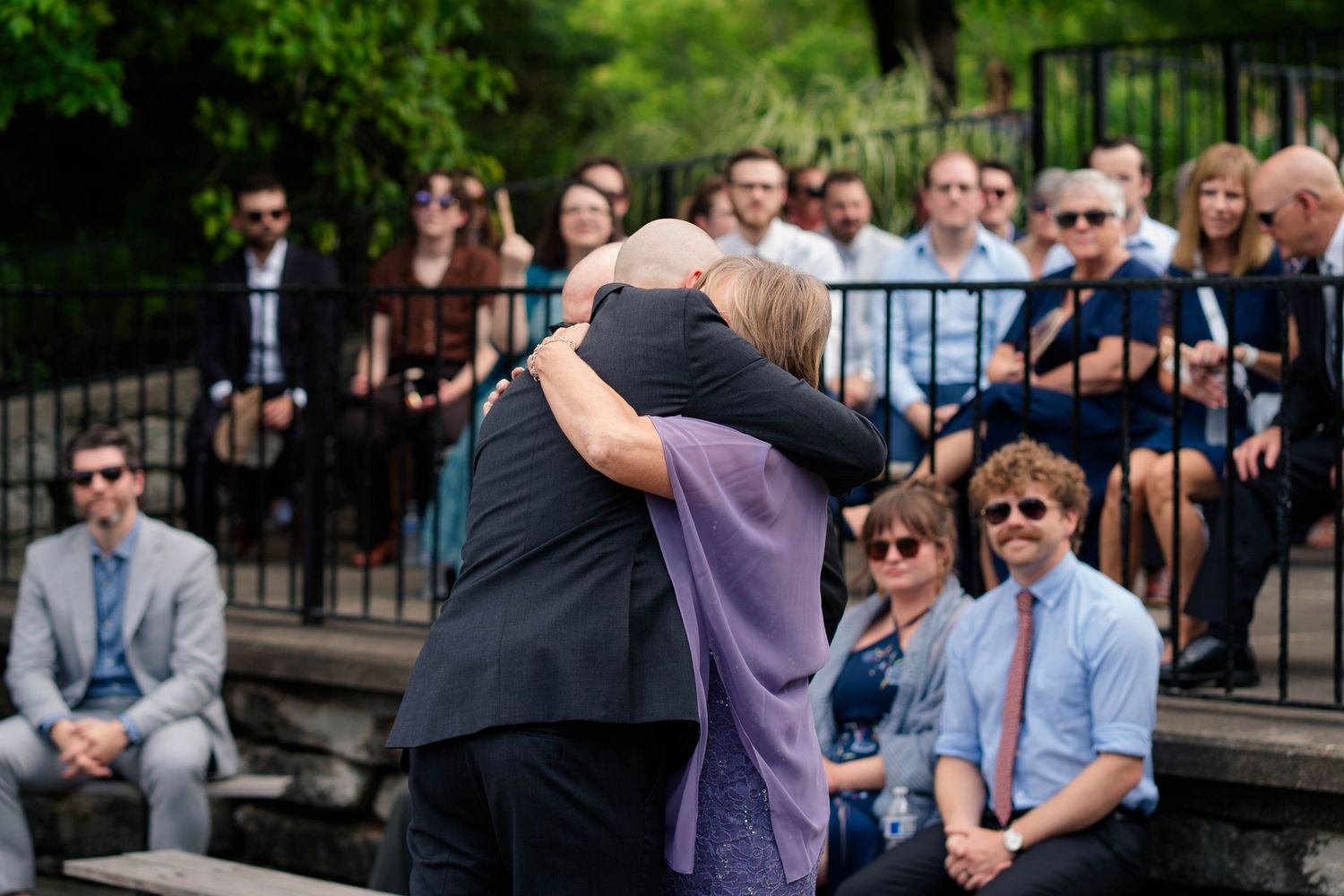 Emotional wedding moment as two people share a heartfelt hug during an outdoor ceremony.