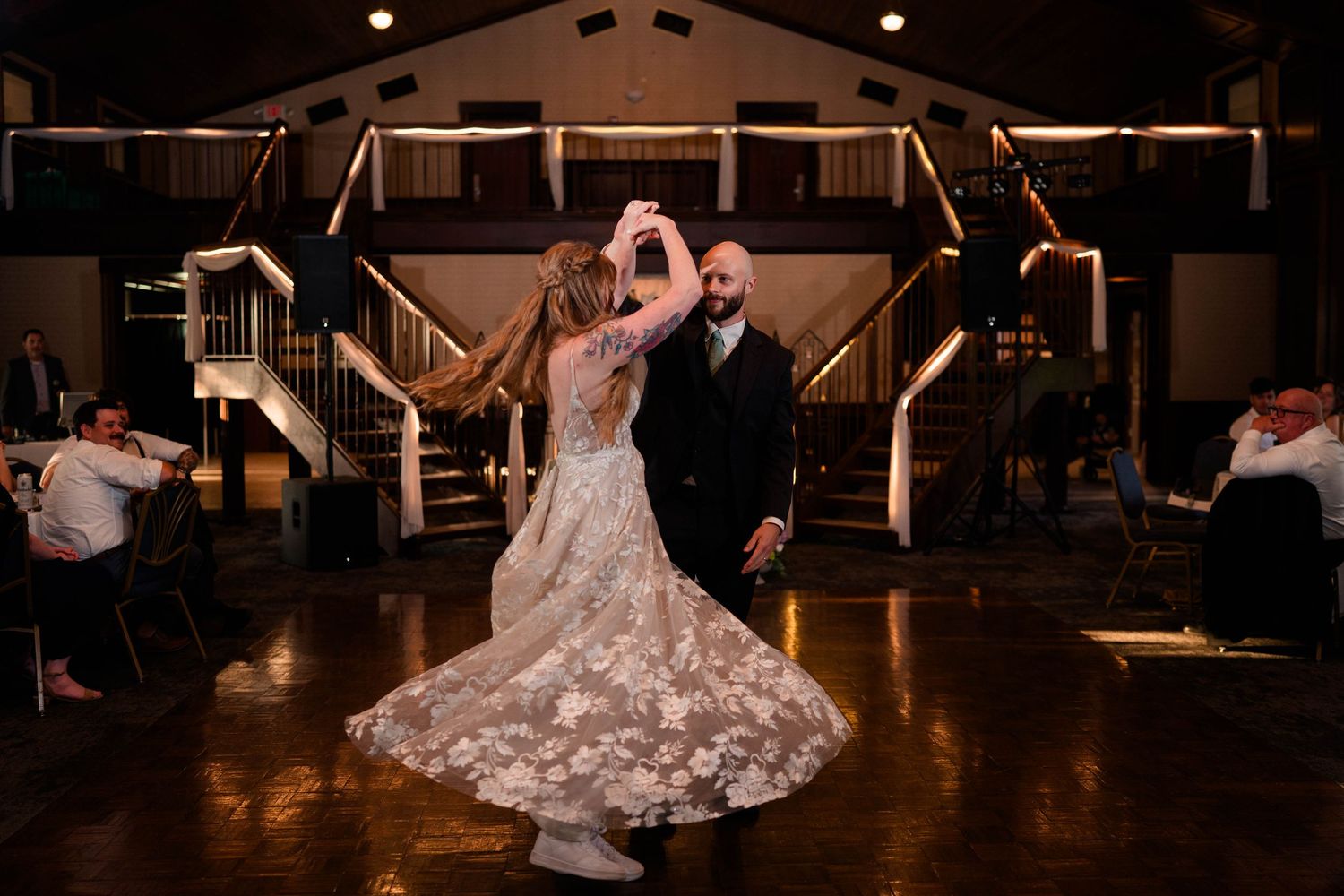 Bride and groom share a romantic first dance, with the bride's floral gown spinning on the dance floor.