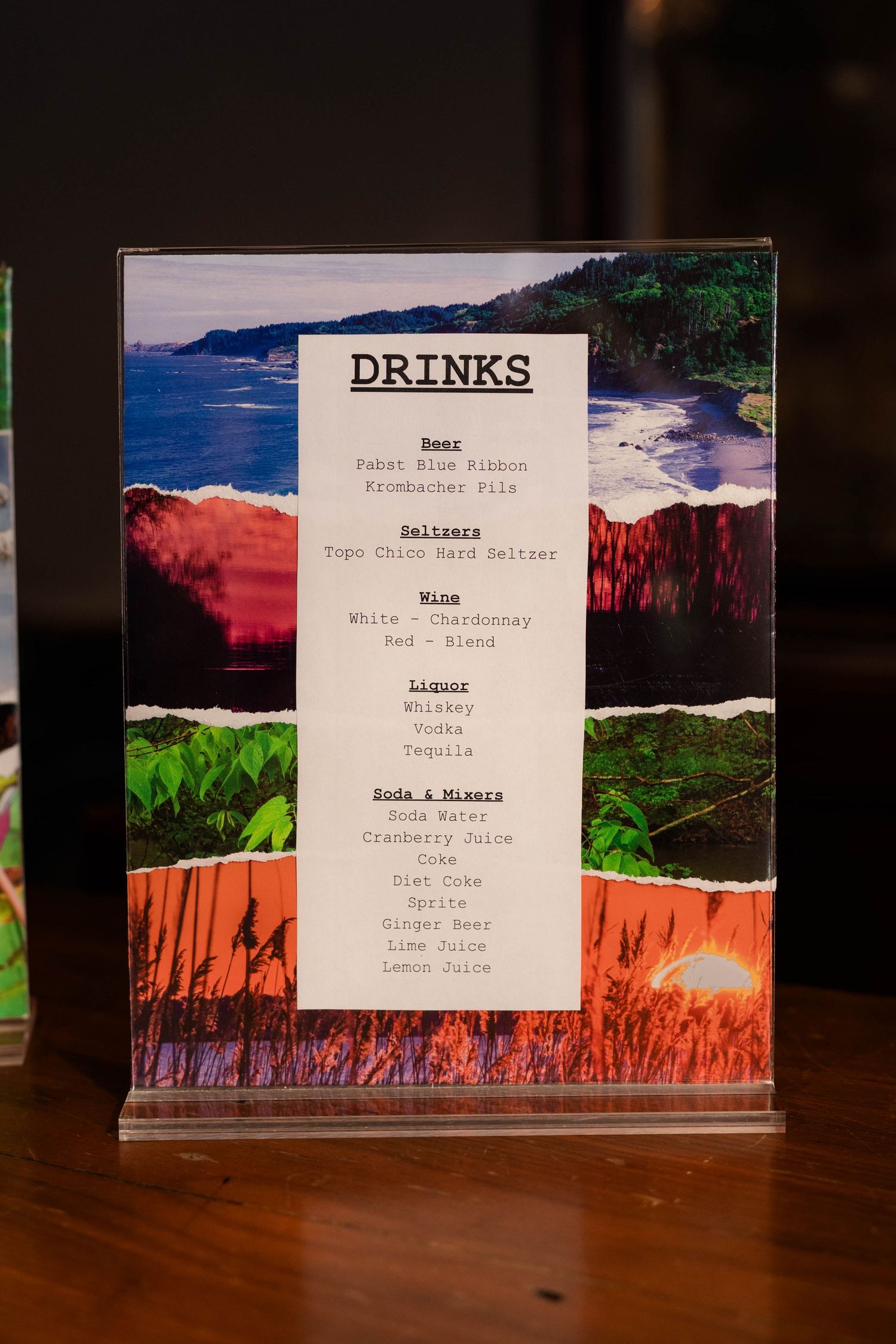 Wedding drinks menu displayed in acrylic holder listing beer, seltzers, wine, liquor, and soda mixers options.