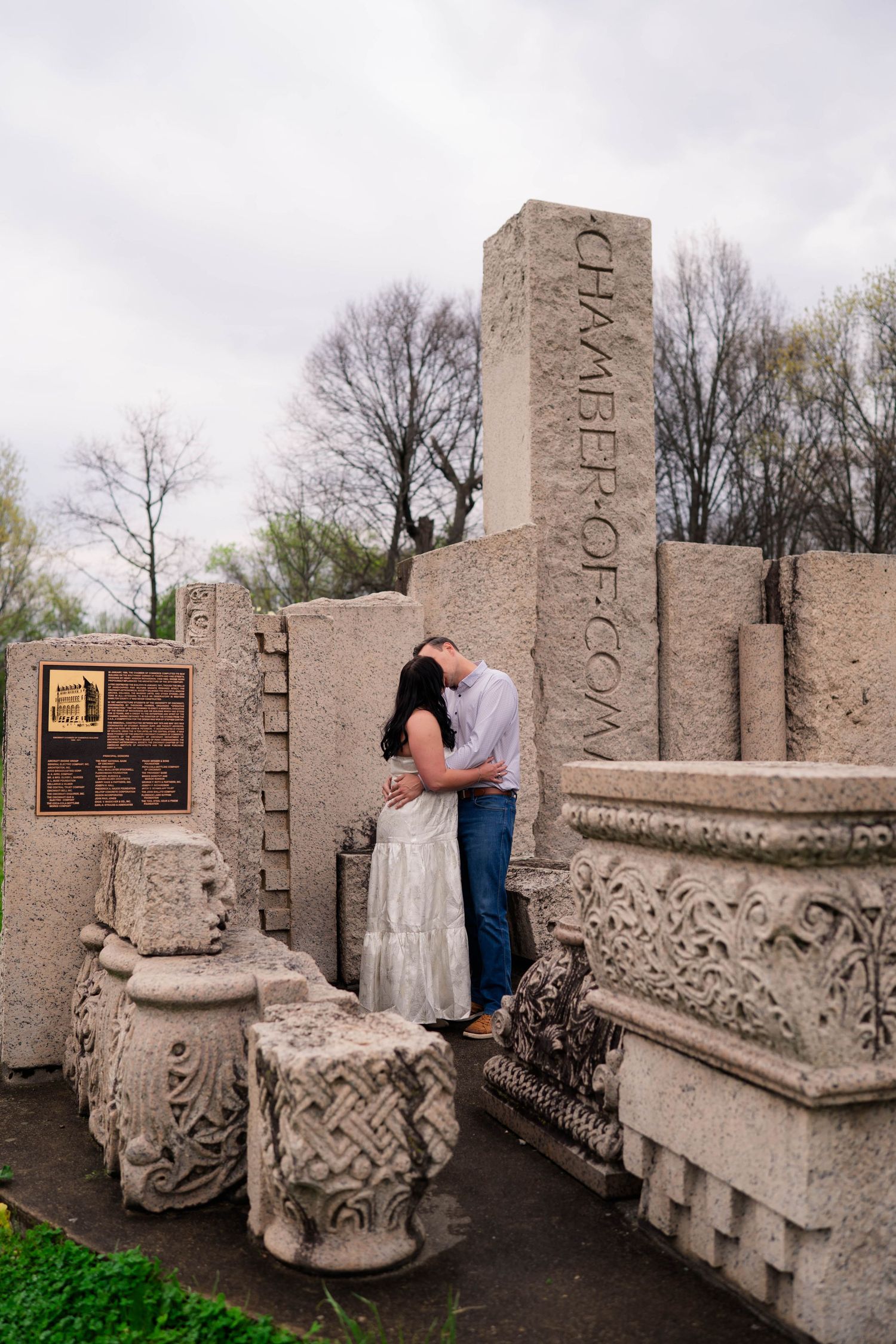Couple kissing among ancient stone ruins at Chamber of Commerce monument outdoors.