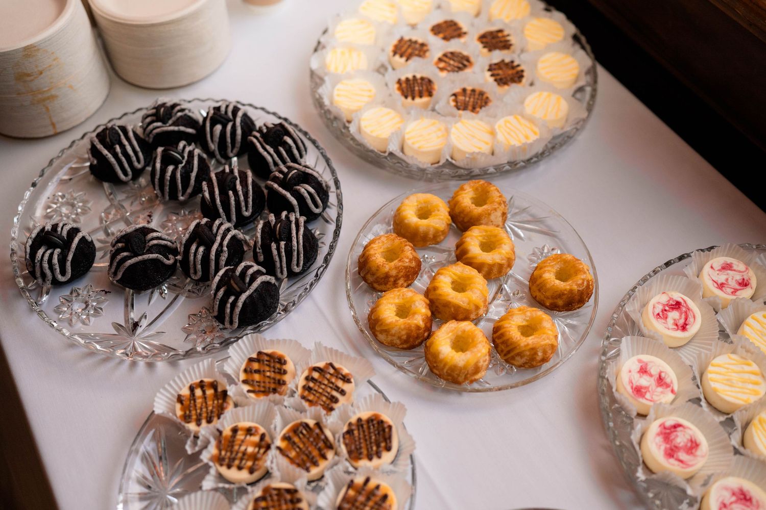 Elegant wedding dessert table featuring chocolate-dipped treats, mini bundt cakes, and frosted petit fours.