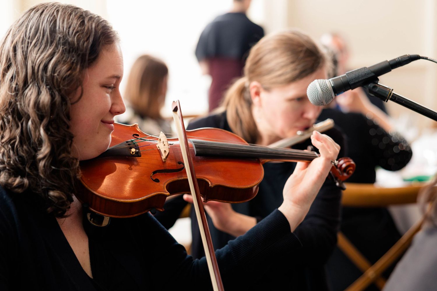 Young woman playing violin at a live music performance during formal event.