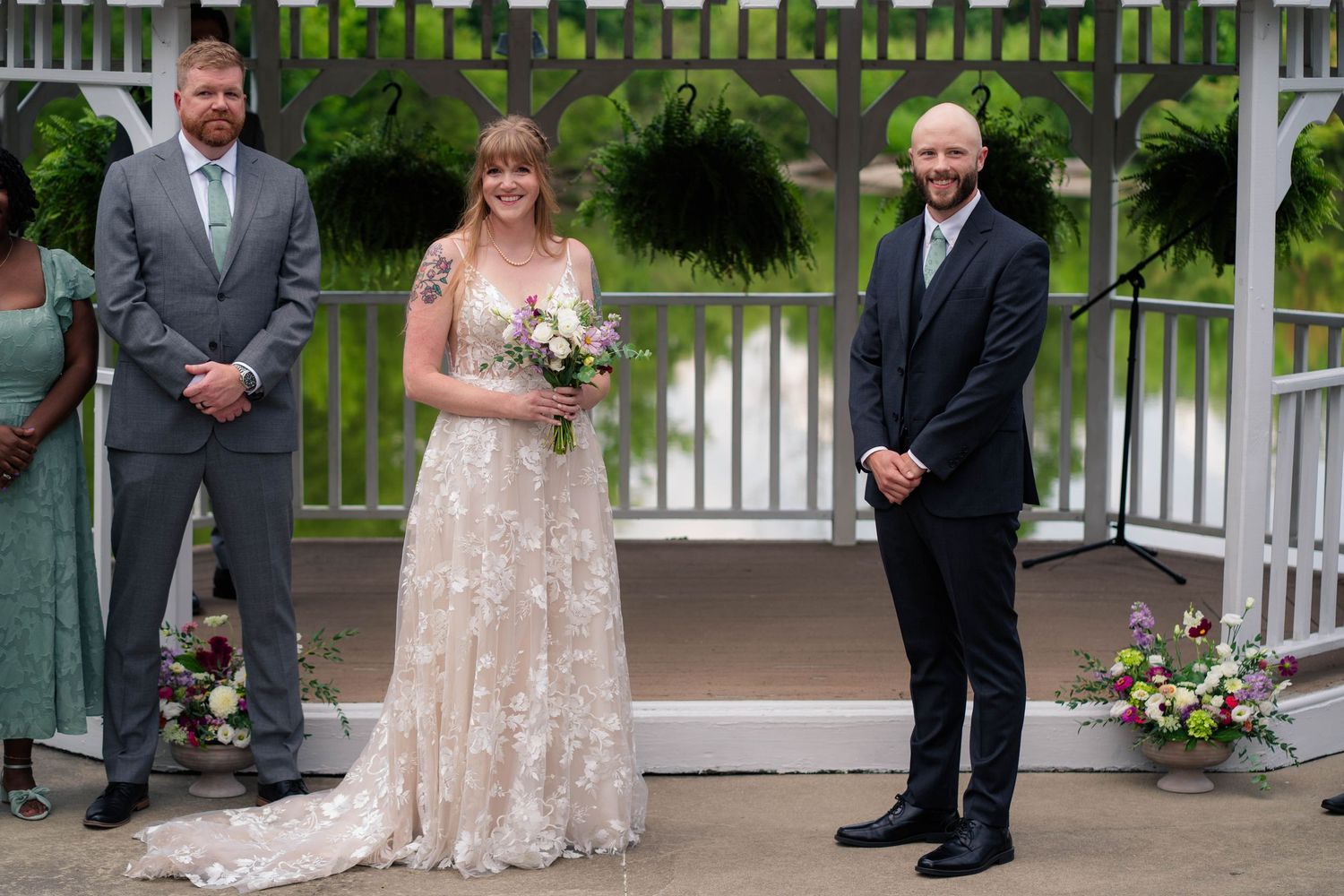 Bride and groom stand with officiant at outdoor gazebo wedding ceremony.