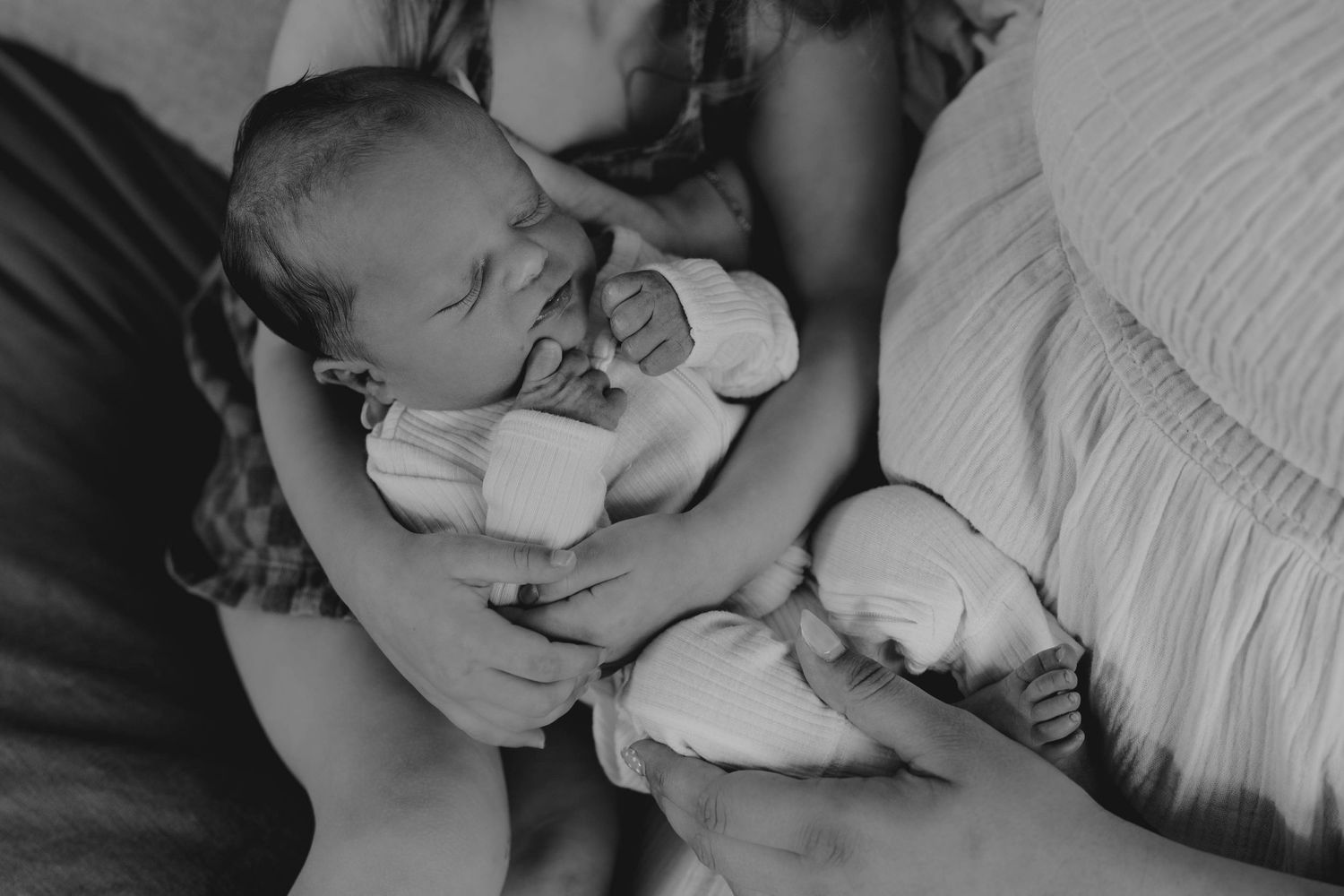 Black and white photo of a mother tenderly cradling her newborn baby in her arms.