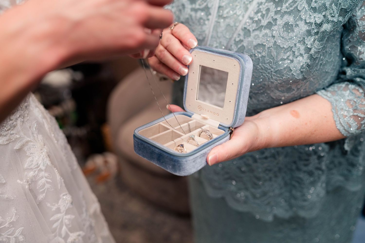 Mother of the bride presenting jewelry from a small velvet box to the bride on her wedding day.