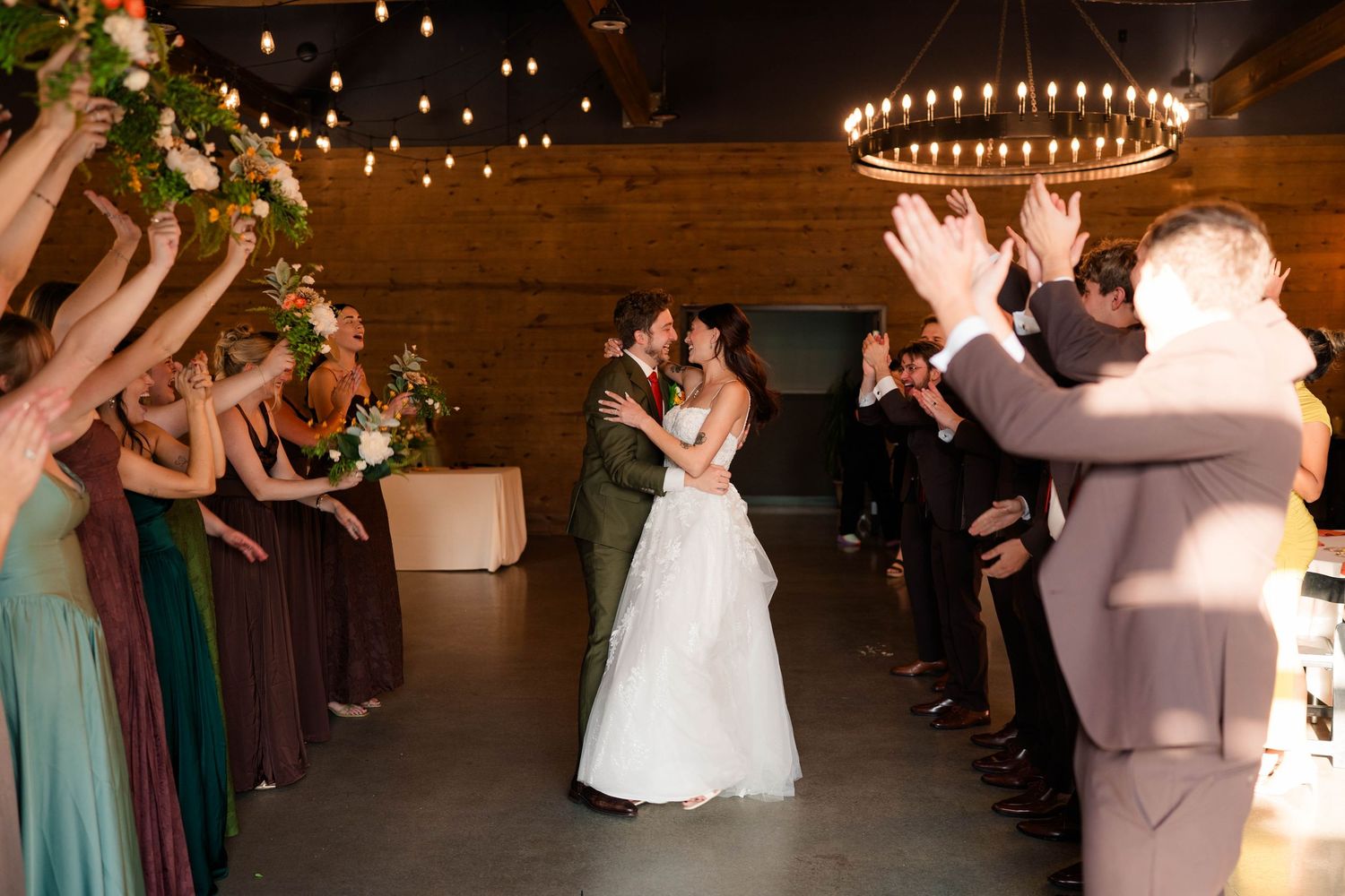 Bride and groom share a first kiss as wedding guests cheer during indoor reception.