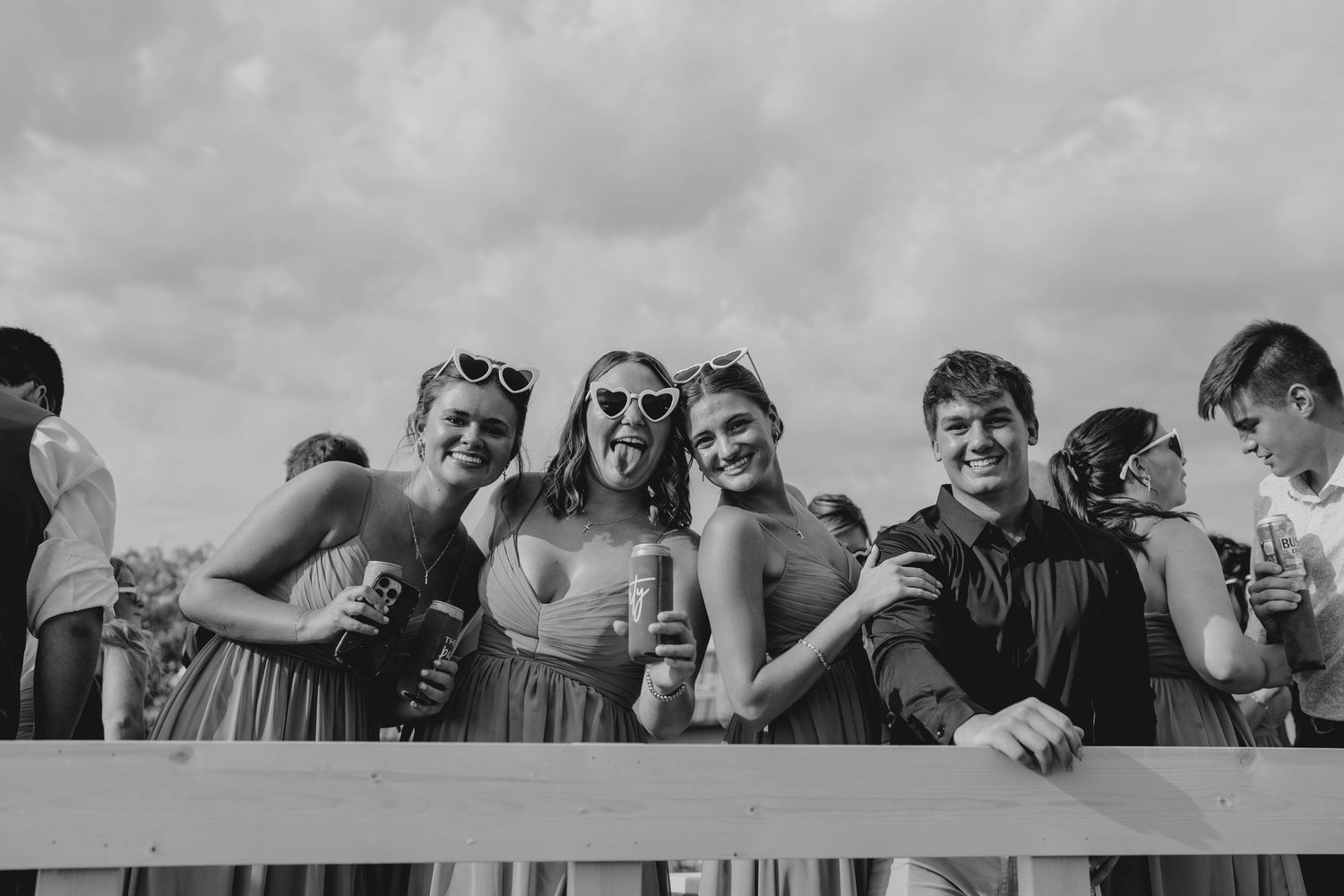 Three bridesmaids and a guest smile and pose together at outdoor wedding reception in black and white photo.
