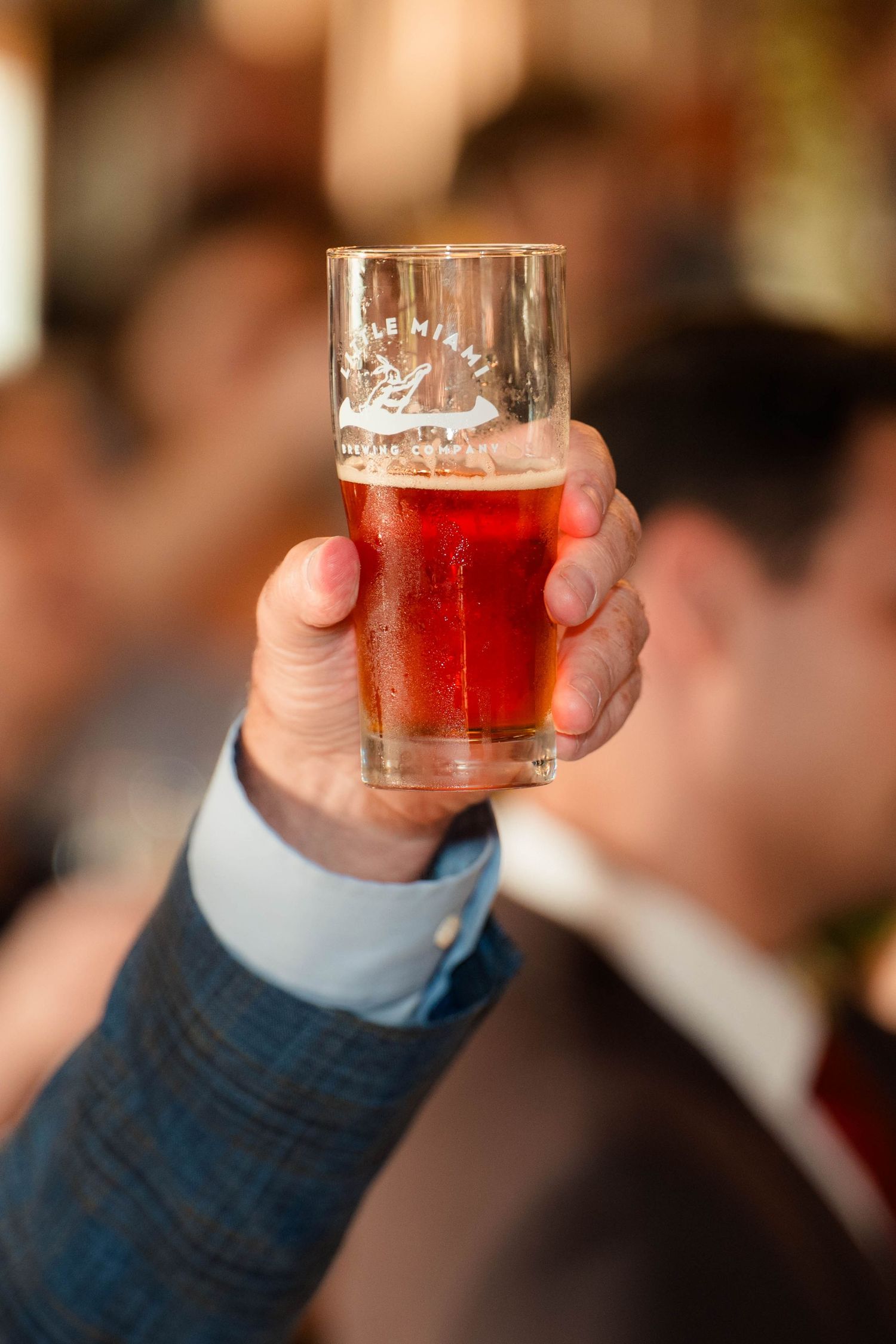 Hand holding a glass of craft beer from Little Miami Brewing at a wedding reception.
