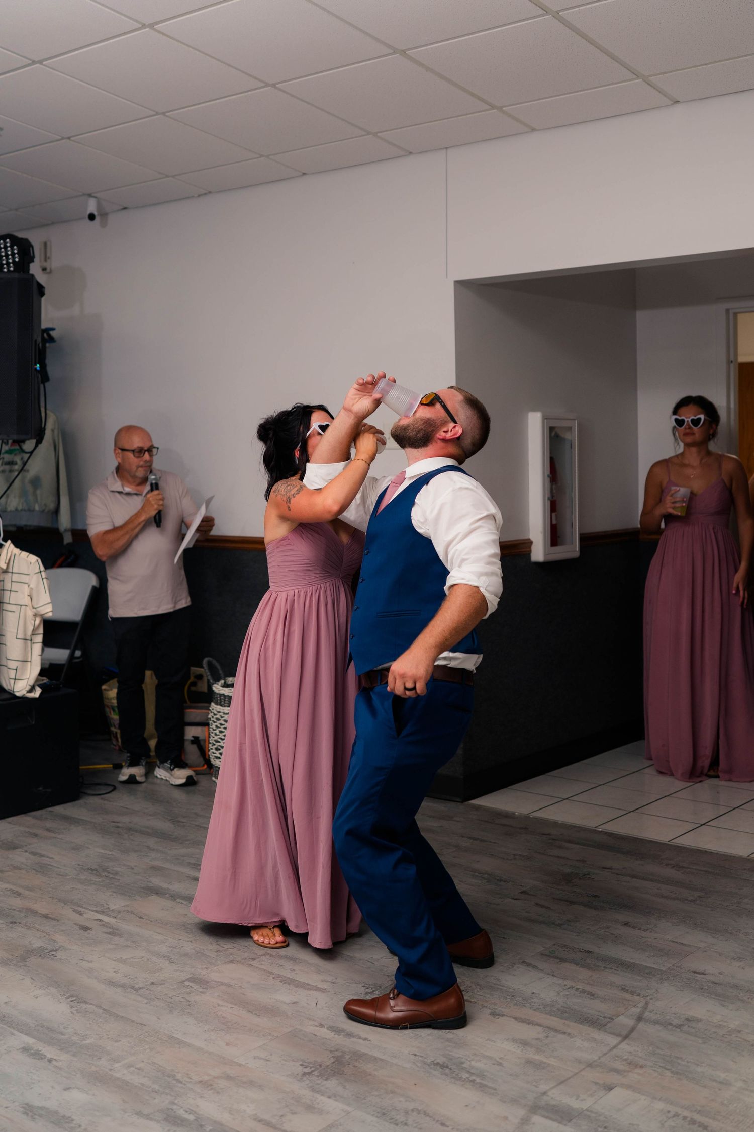 Couple dancing energetically at wedding reception while guests watch and photograph the moment.