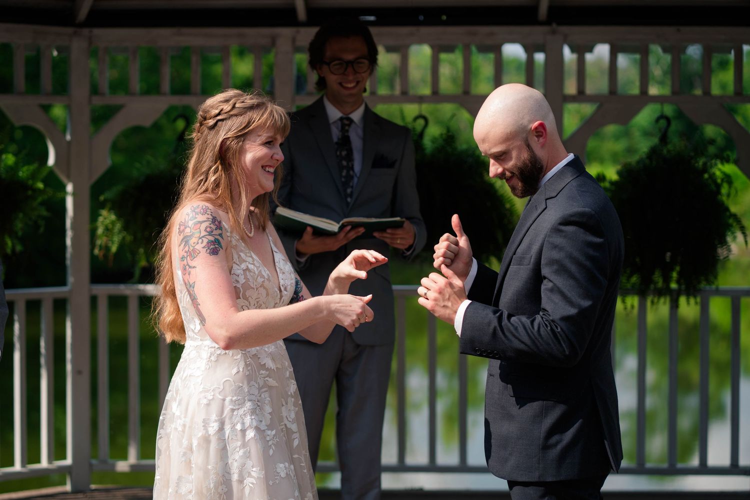 Bride and groom laughing during outdoor wedding ring exchange ceremony at a gazebo.