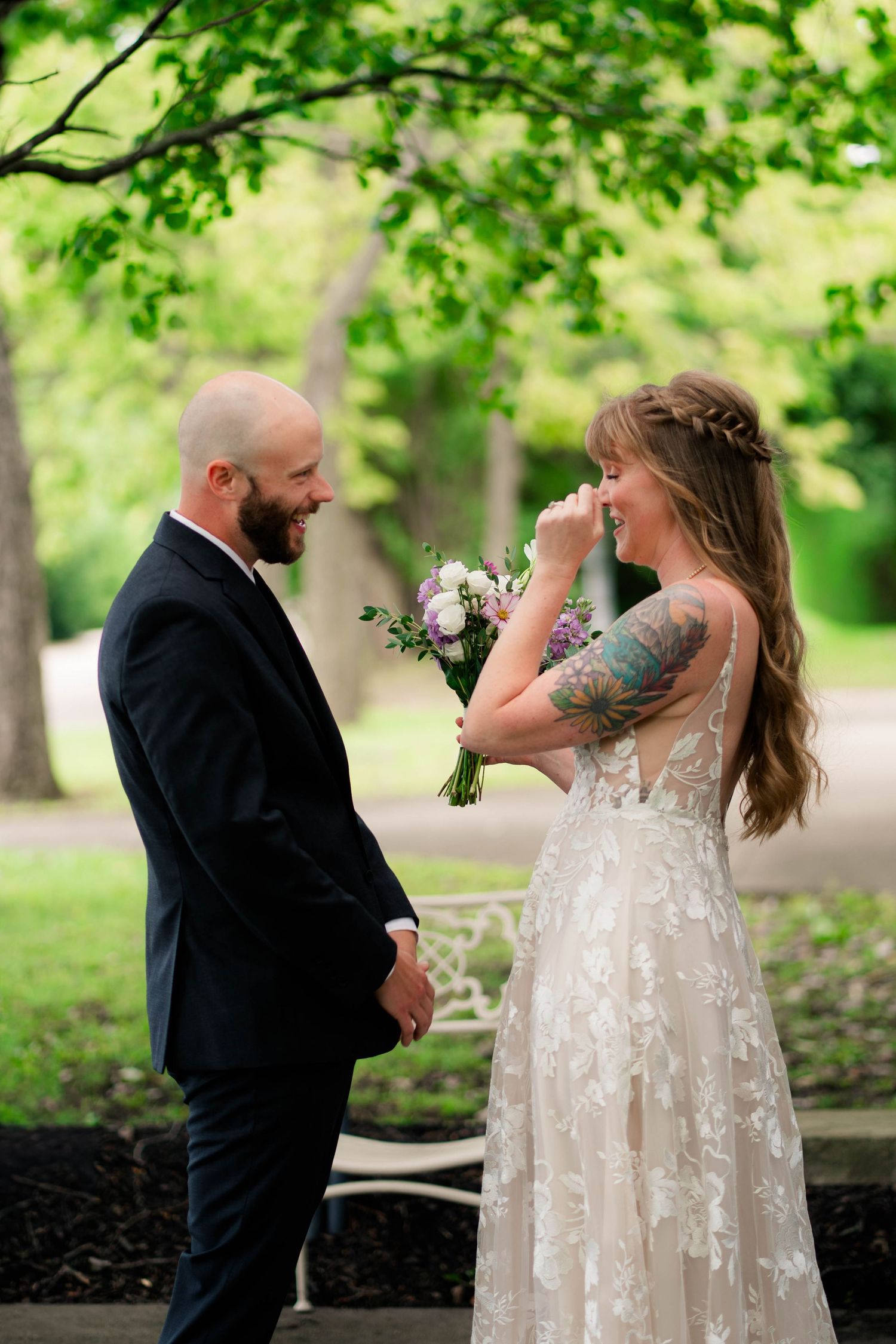 Emotional bride and groom share first look moment in lush green park setting.