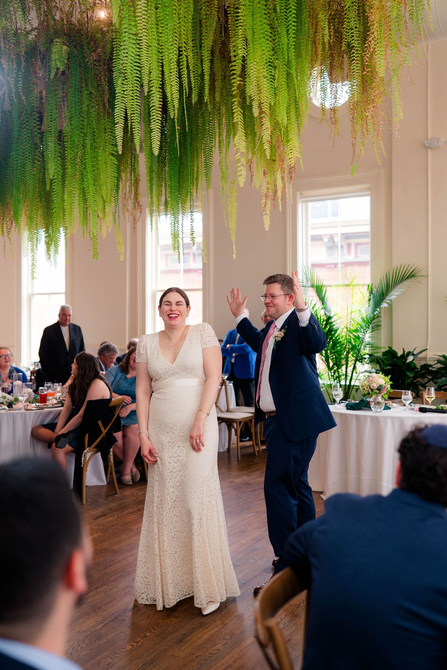 Smiling bride and groom waving to guests after first dance at botanical wedding reception.