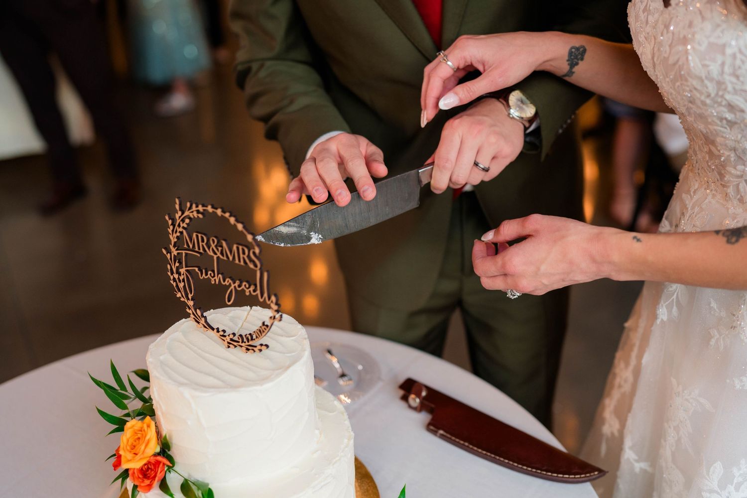 Bride and groom cutting white wedding cake with floral decorations and Mr. and Mrs. cake topper.