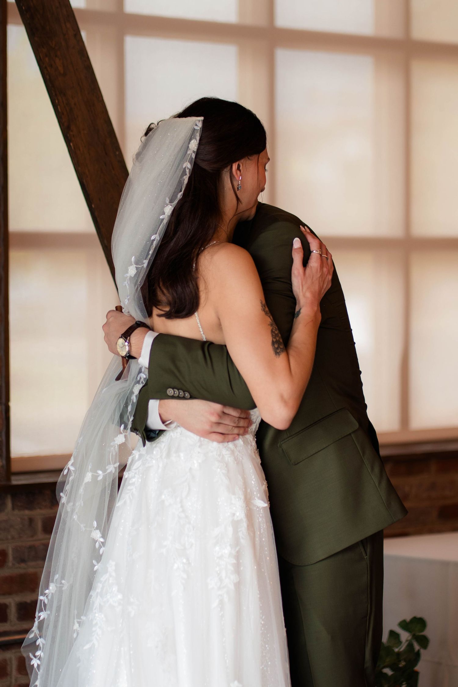 Bride and groom sharing an emotional embrace during wedding ceremony in a rustic brick venue.
