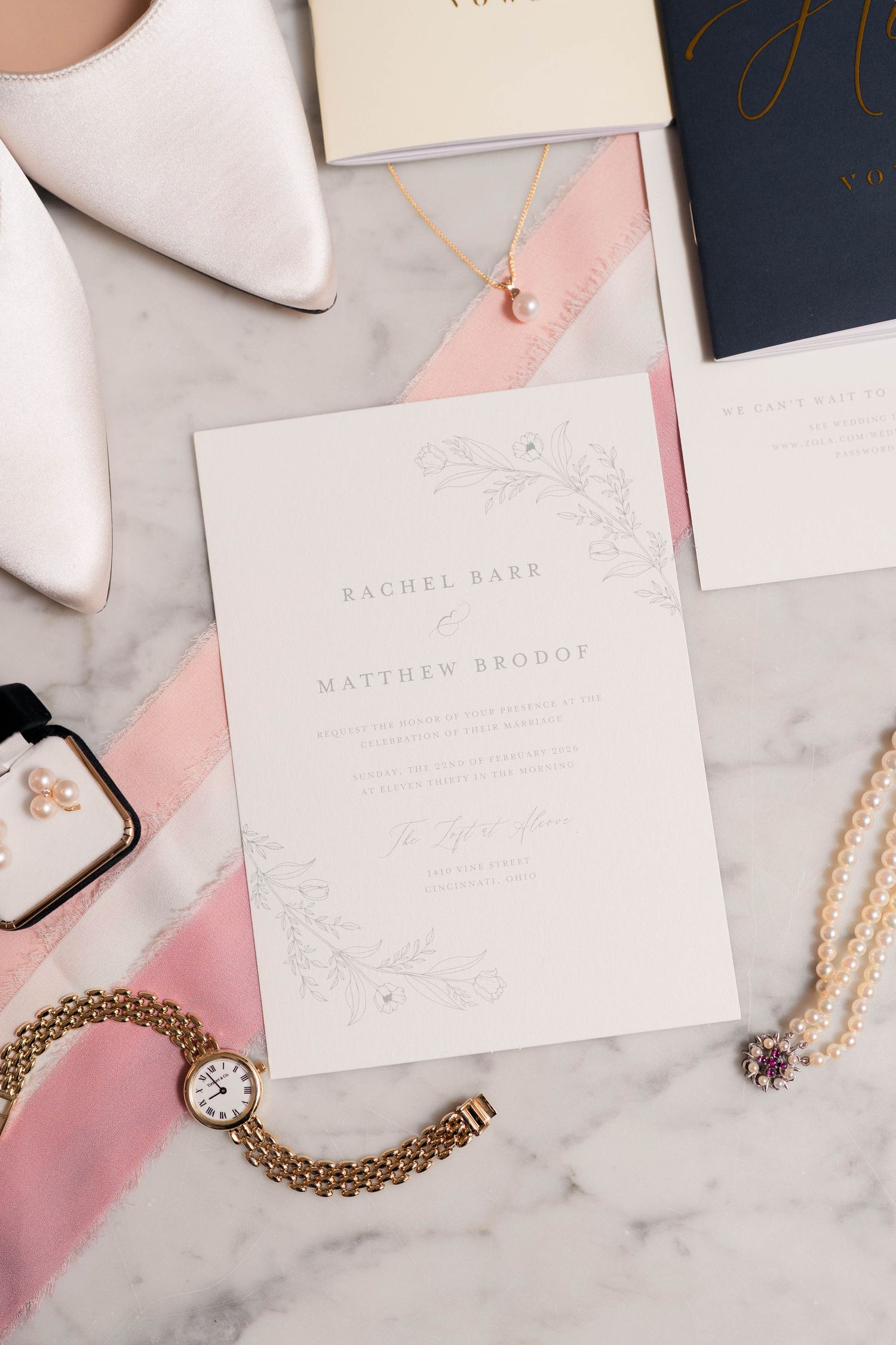 Elegant wedding invitation suite for Rachel Barr and Matthew Brodof with pink ribbon and gold jewelry.