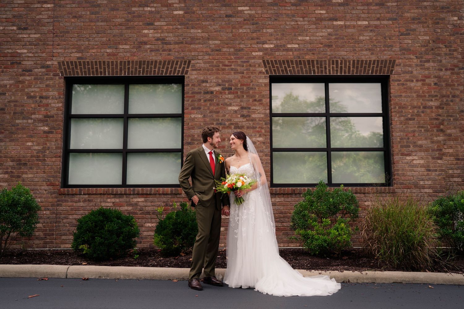 Bride and groom share a romantic moment outside a brick building on their wedding day.